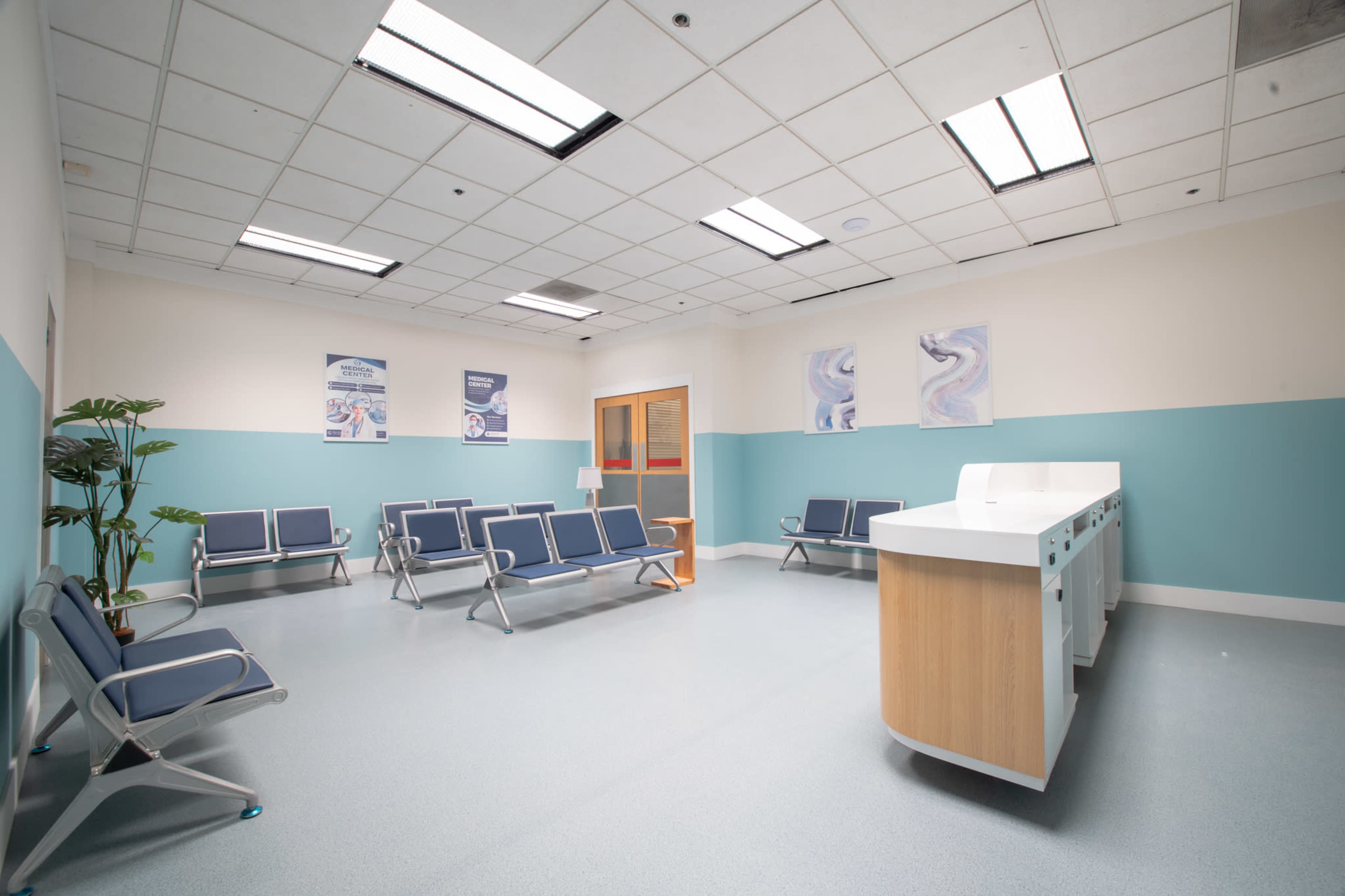 The image shows a waiting room with metal and fabric chairs, a reception desk, and decorative posters on the walls.