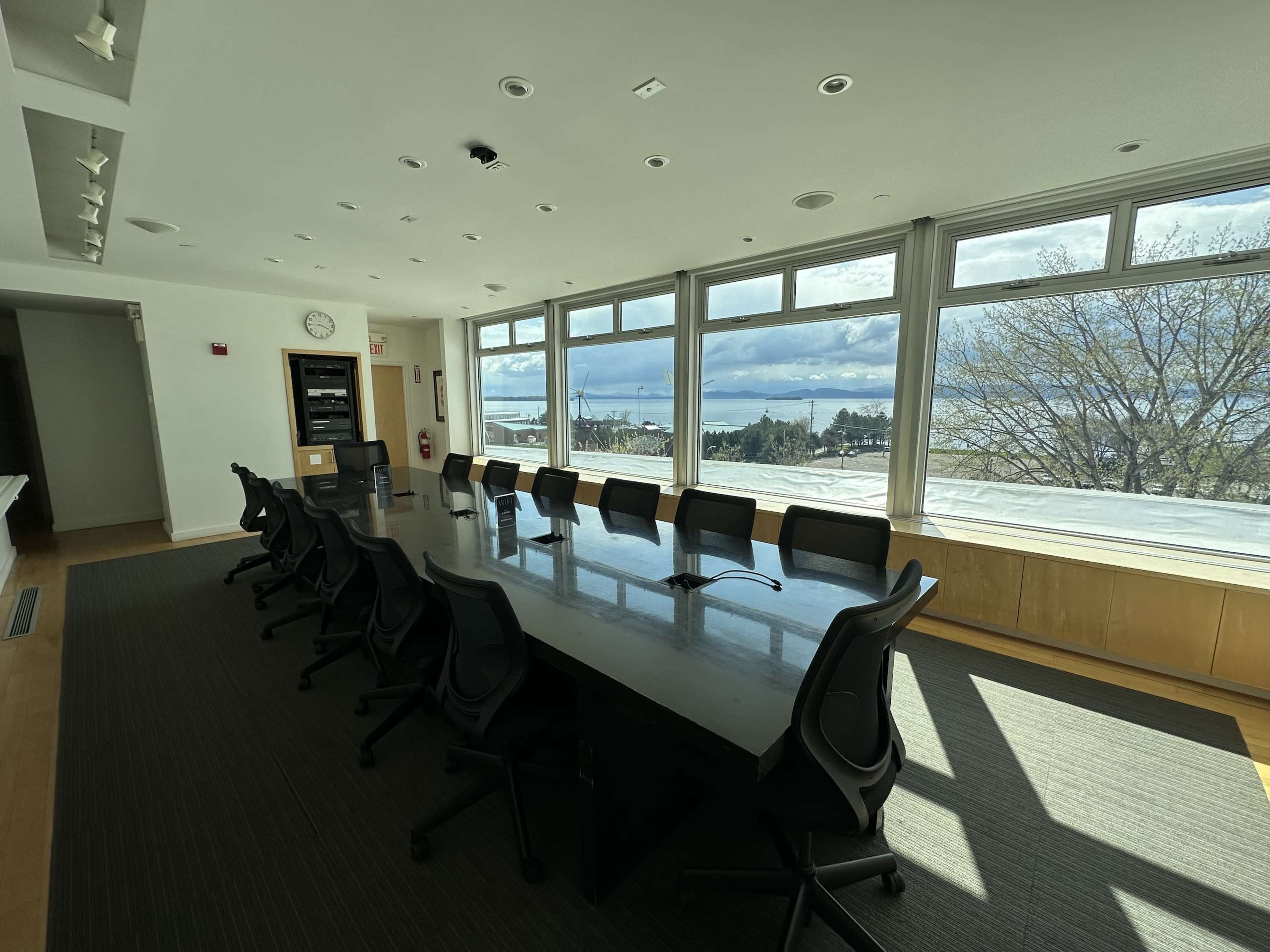 A large conference room with a long table and chairs facing windows that offer a view of the outdoors.