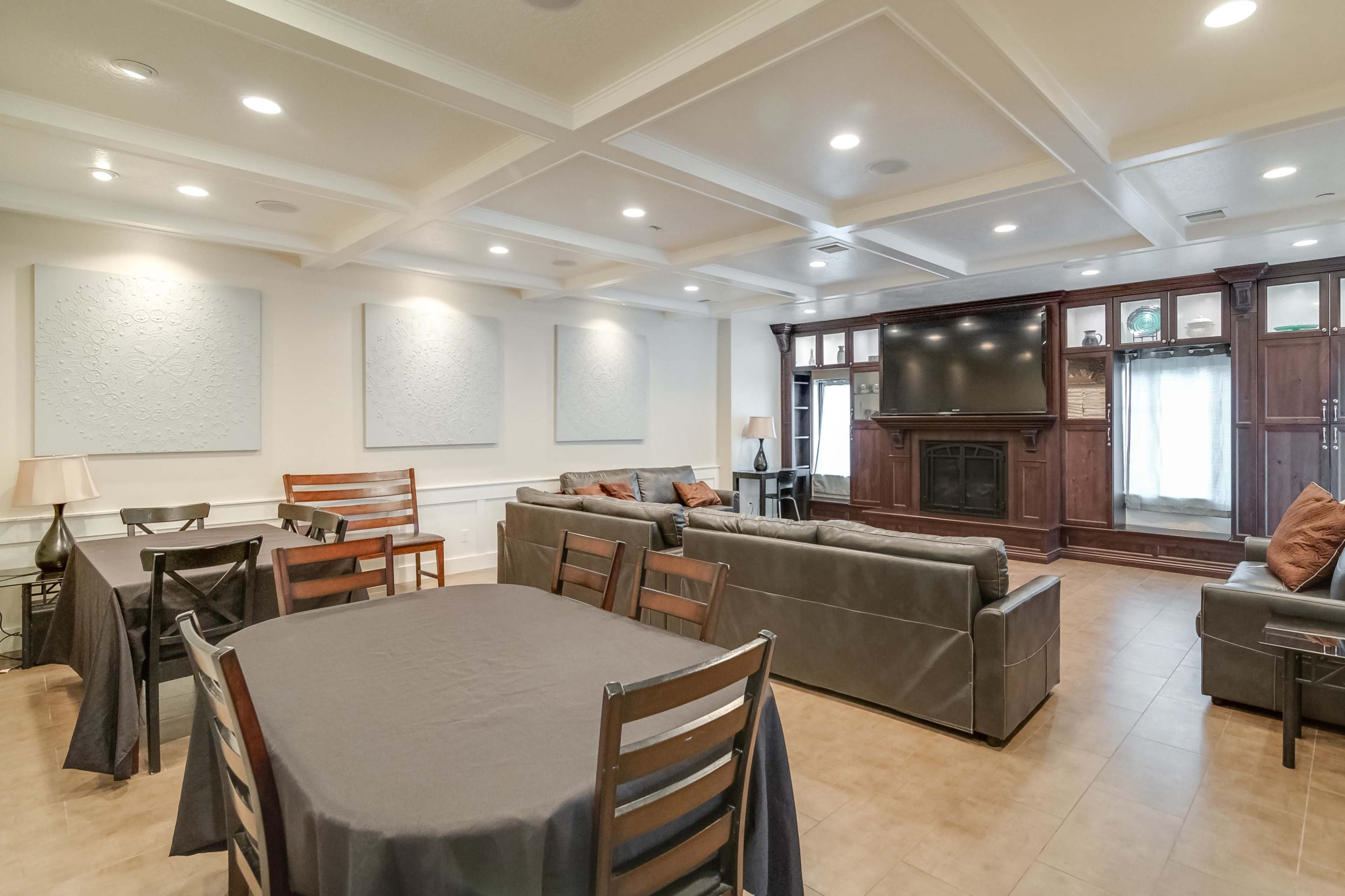 The room features a spacious layout with multiple seating areas, a television unit, and tables covered with dark tablecloths.