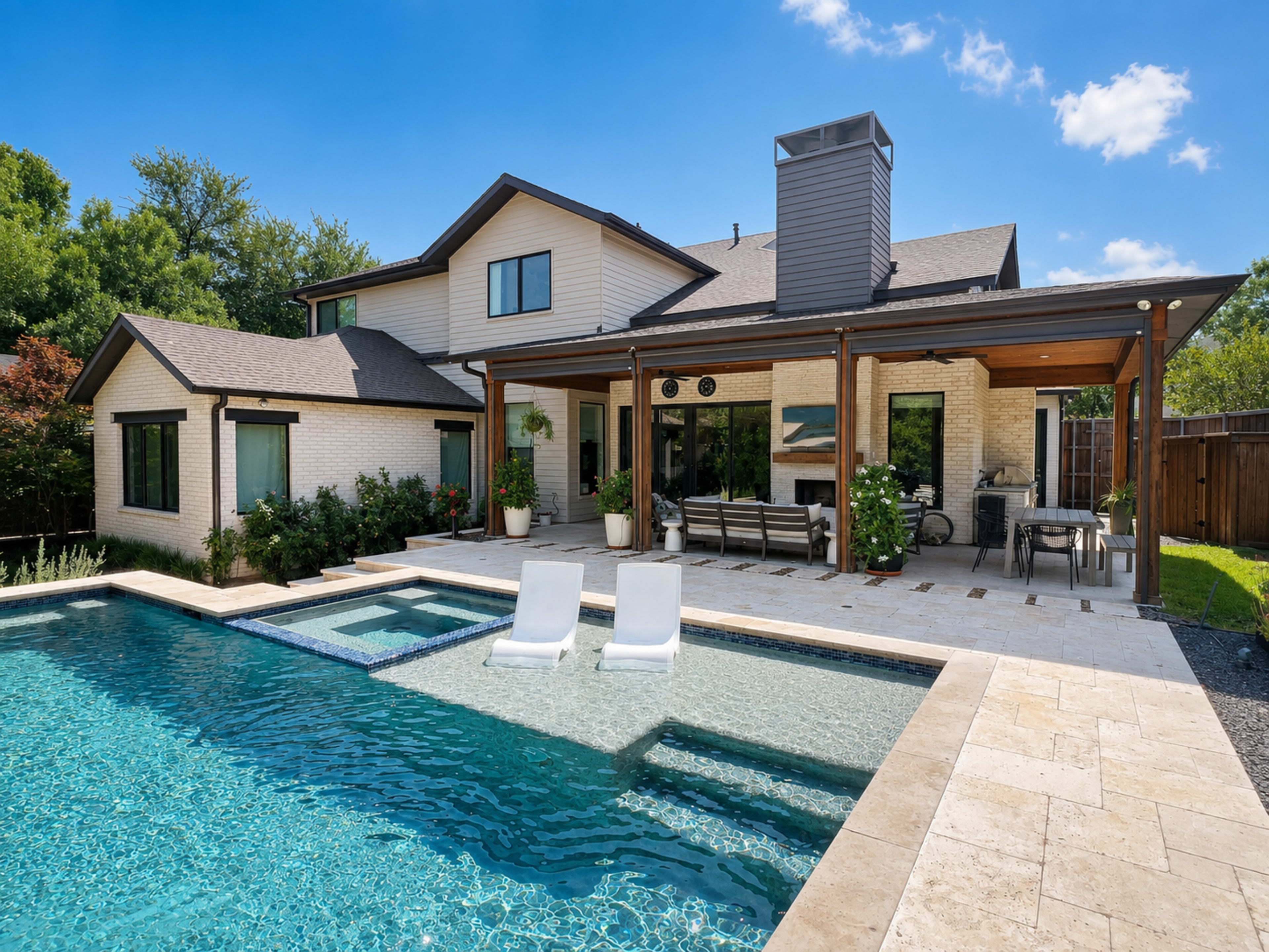 A modern two-story house with a swimming pool and a covered patio featuring outdoor furniture and landscaping around the property.