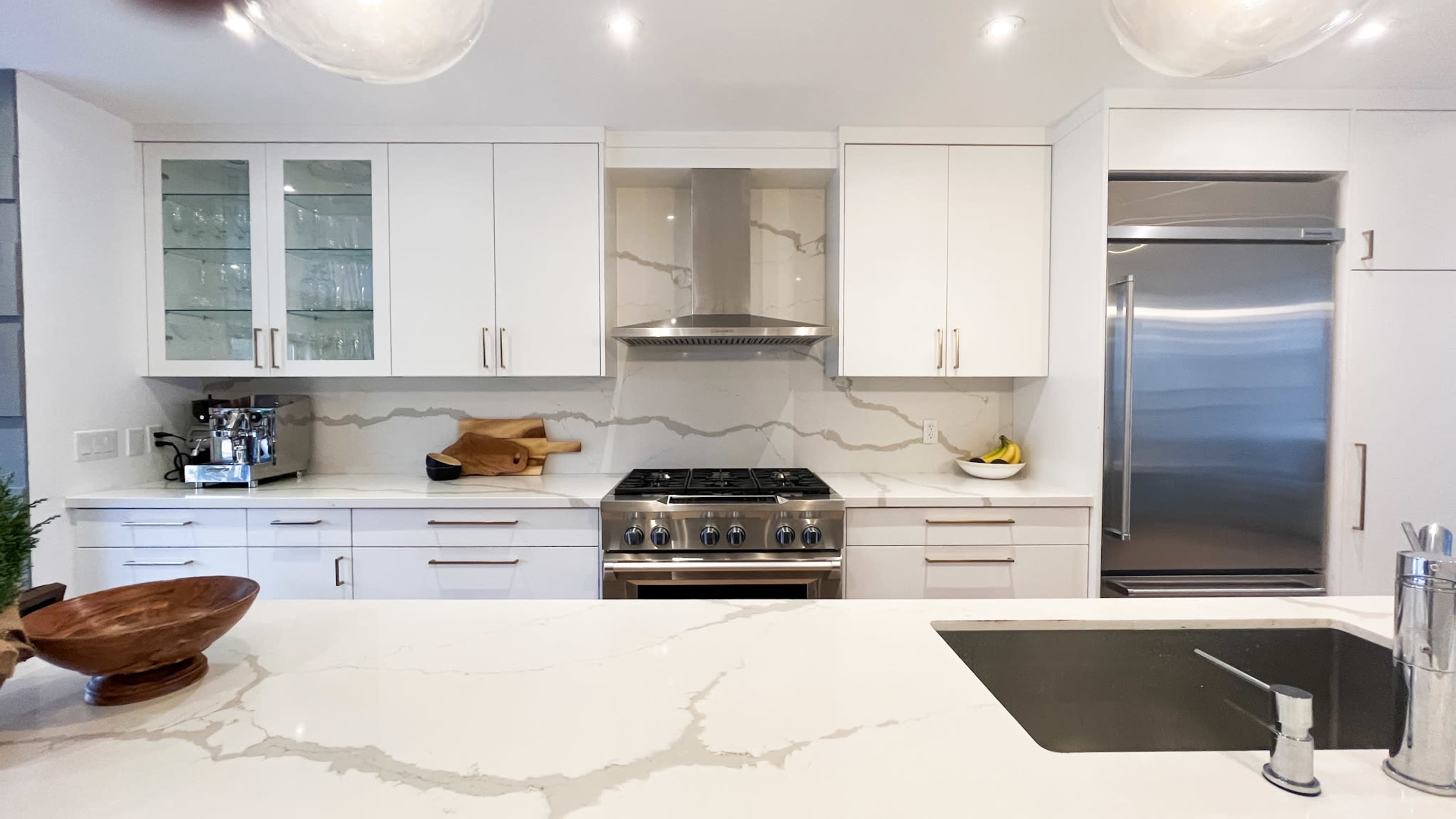 The kitchen features white cabinetry, a stainless steel stove with an overhead vent, and a marble backsplash.