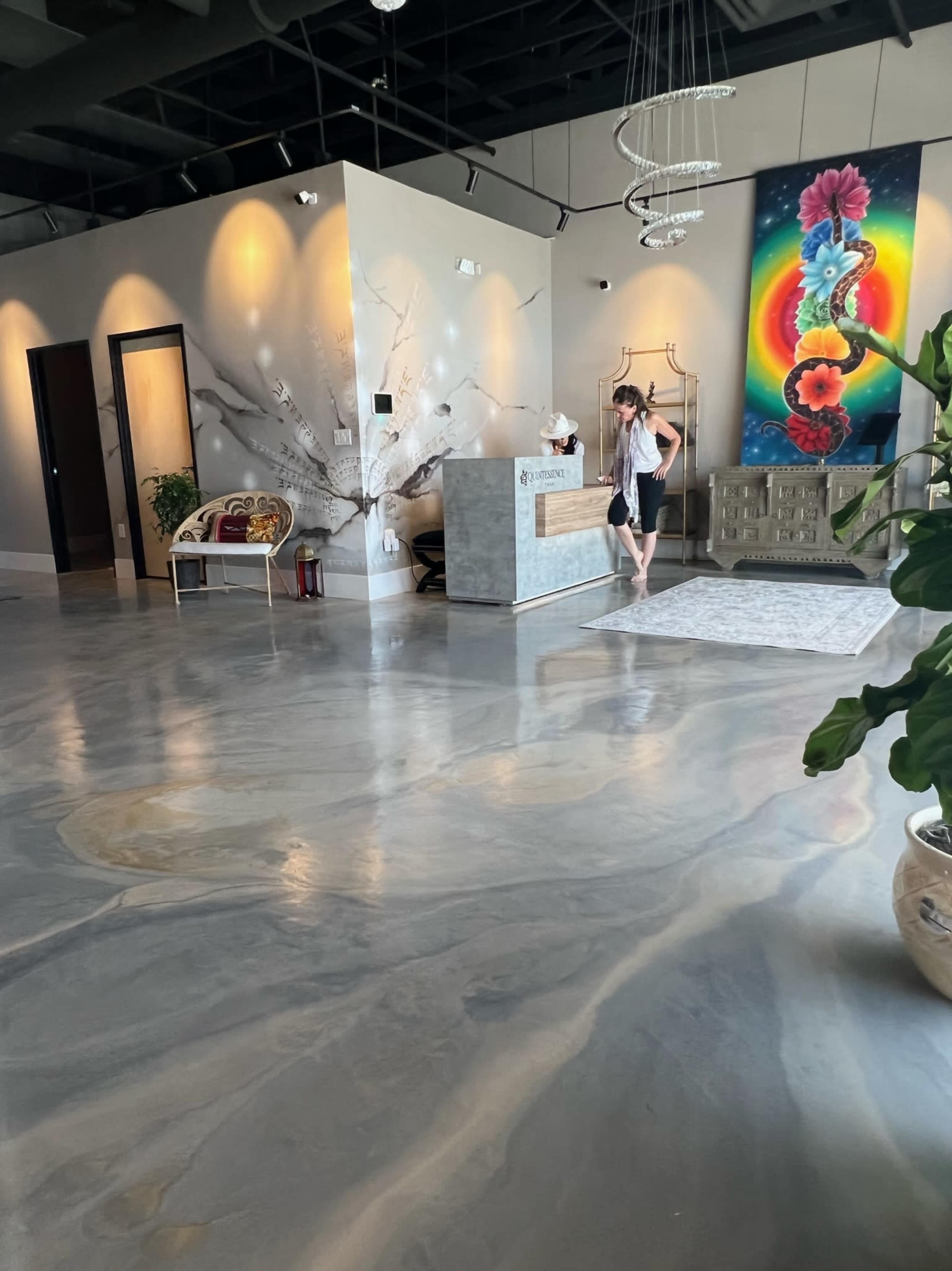 A woman stands in a modern reception area with polished concrete floors and decorative artwork on the walls.