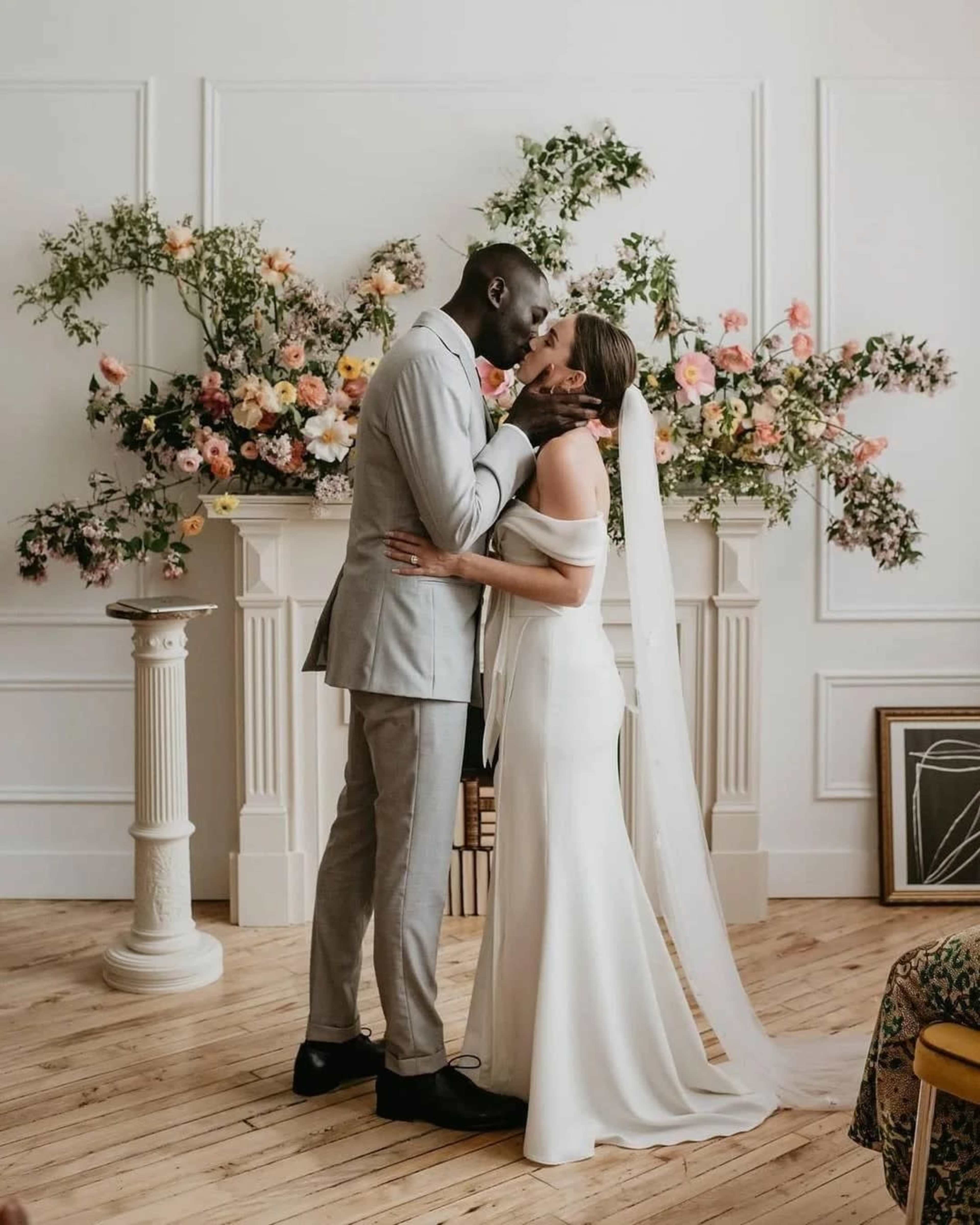 A couple is exchanging vows in front of a floral arrangement during their wedding ceremony.