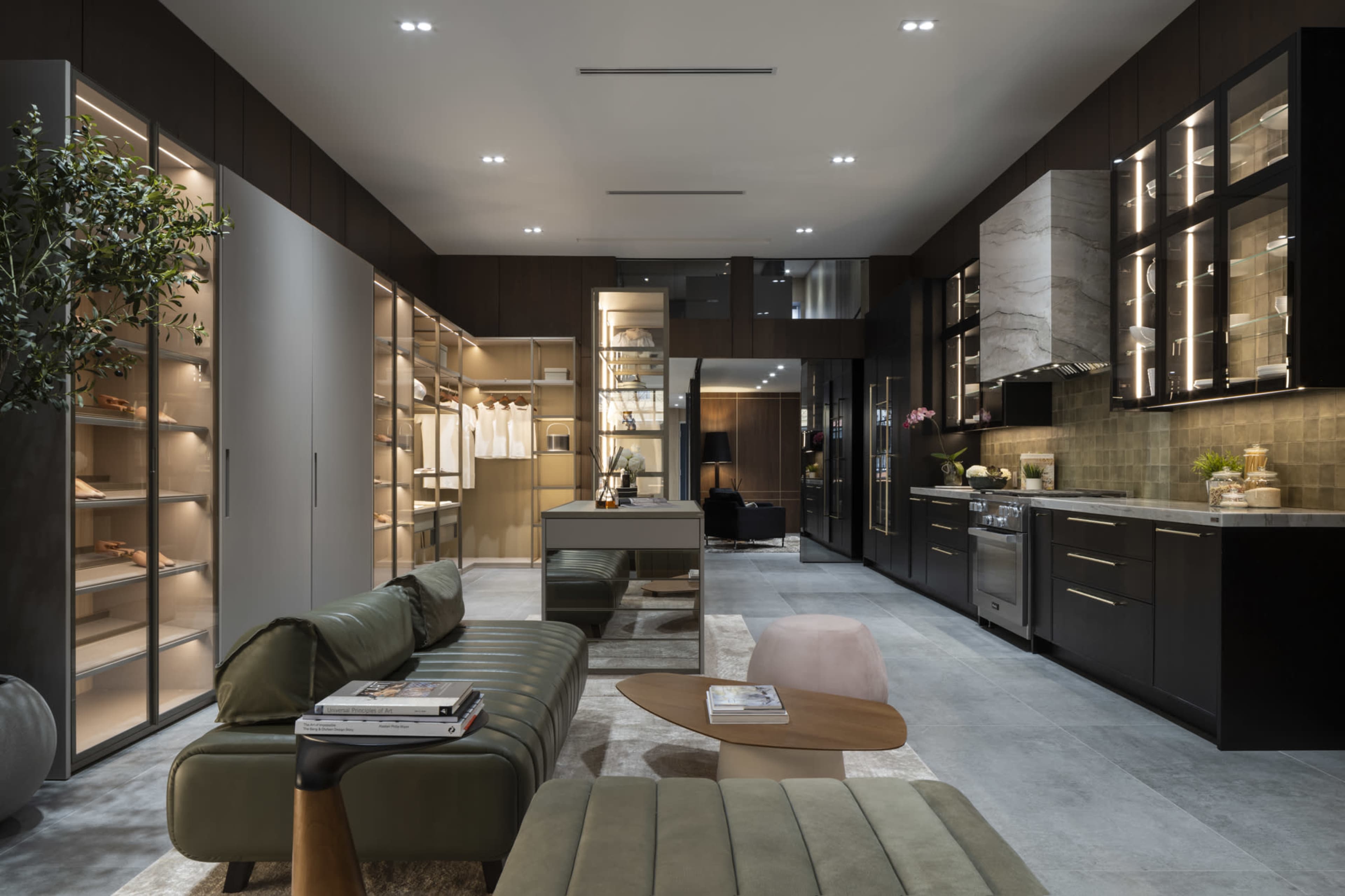 A modern kitchen and living space features sleek cabinets, a central island, and a green sofa, complemented by warm lighting and contemporary decor.