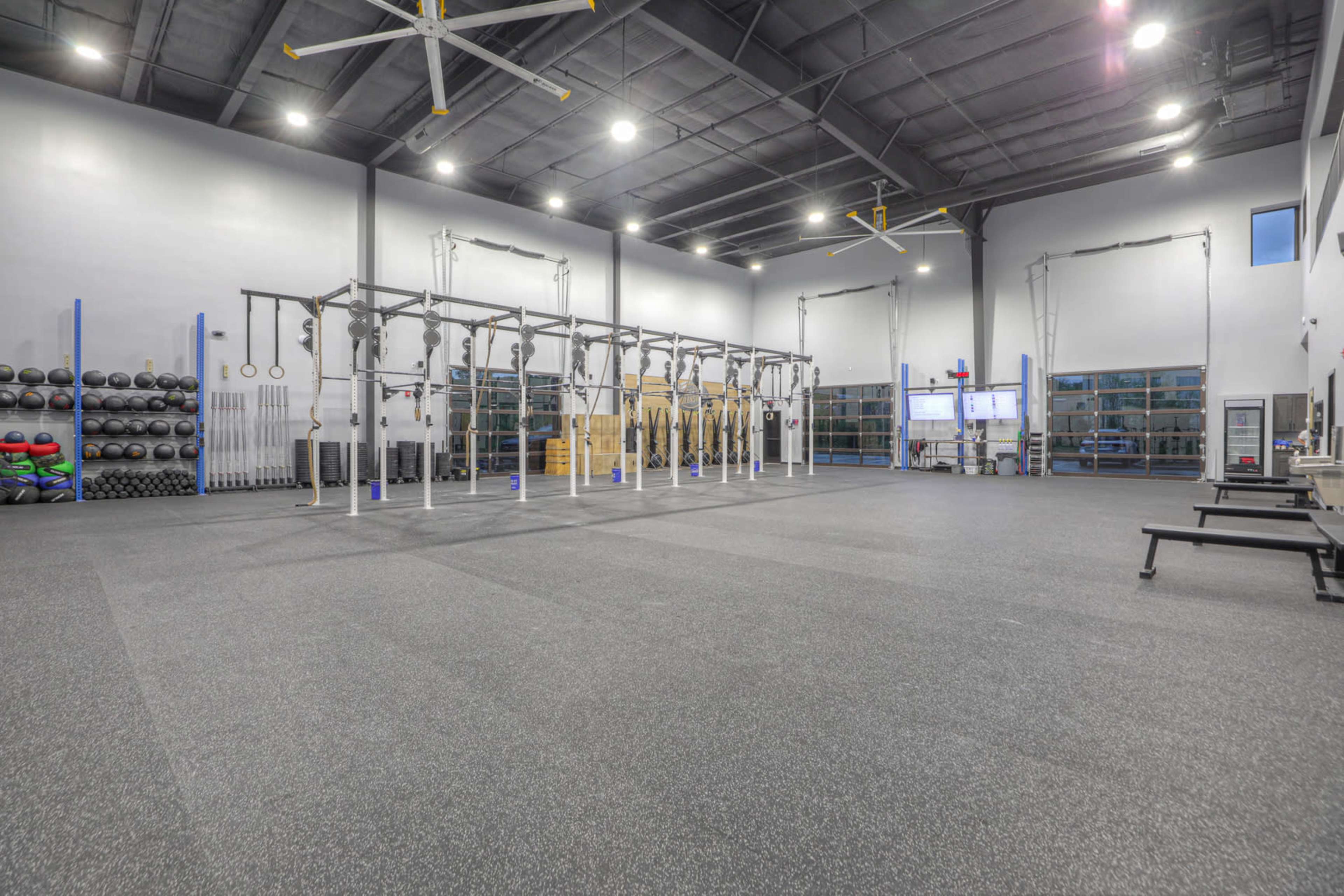 The image shows an indoor gym with various exercise equipment, including free weights and a multi-functional rig for workouts.