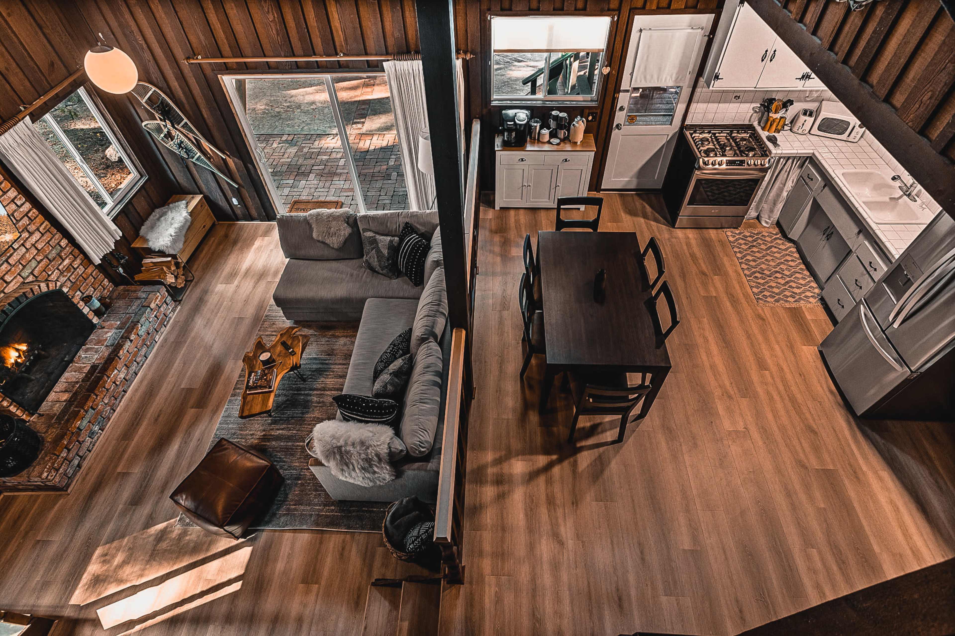 A spacious living area with a gray sectional sofa and a dining table beside a kitchen in a modern cabin setting.