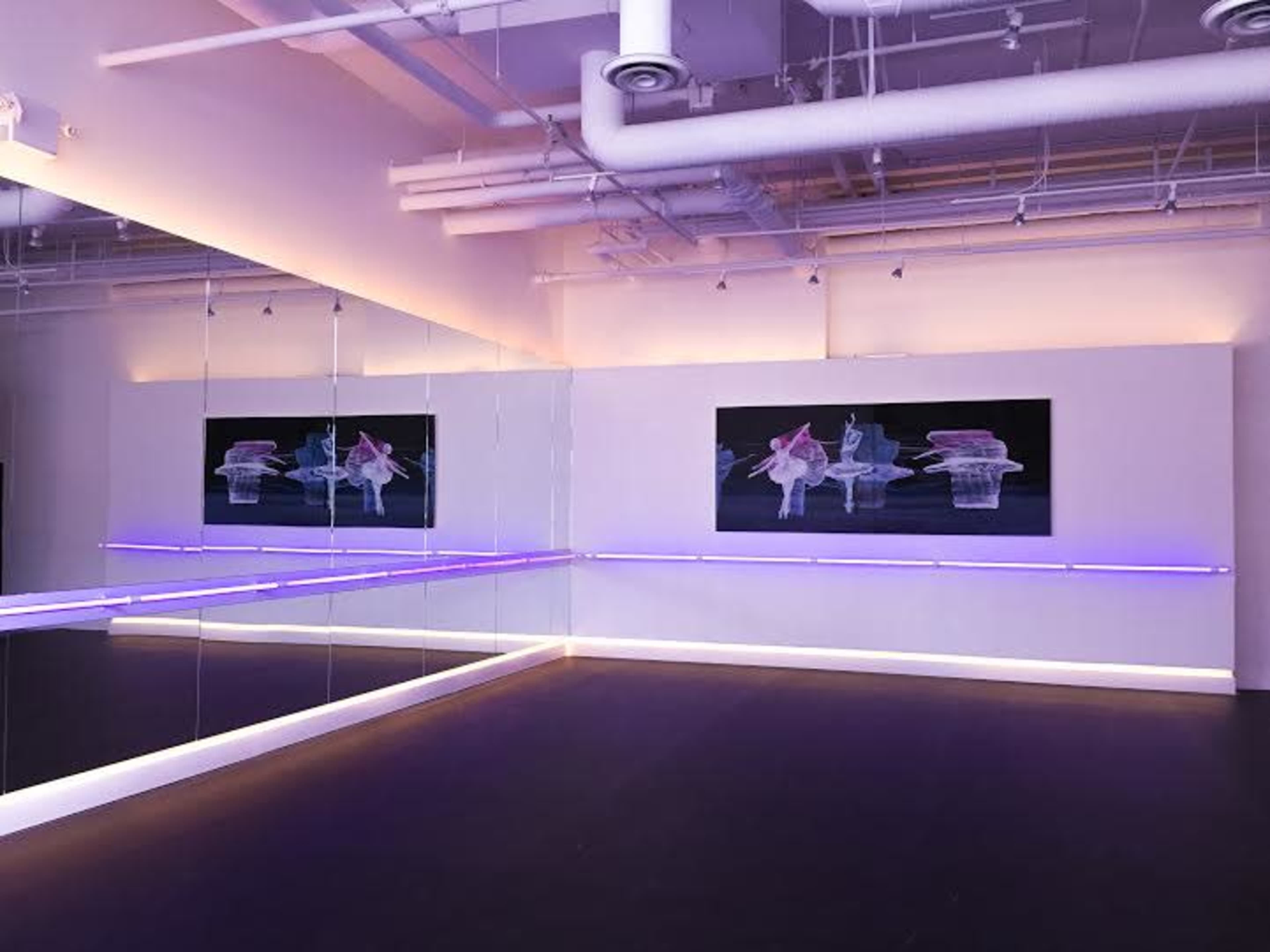 A modern dance studio featuring mirrored walls, soft lighting, and abstract artwork.