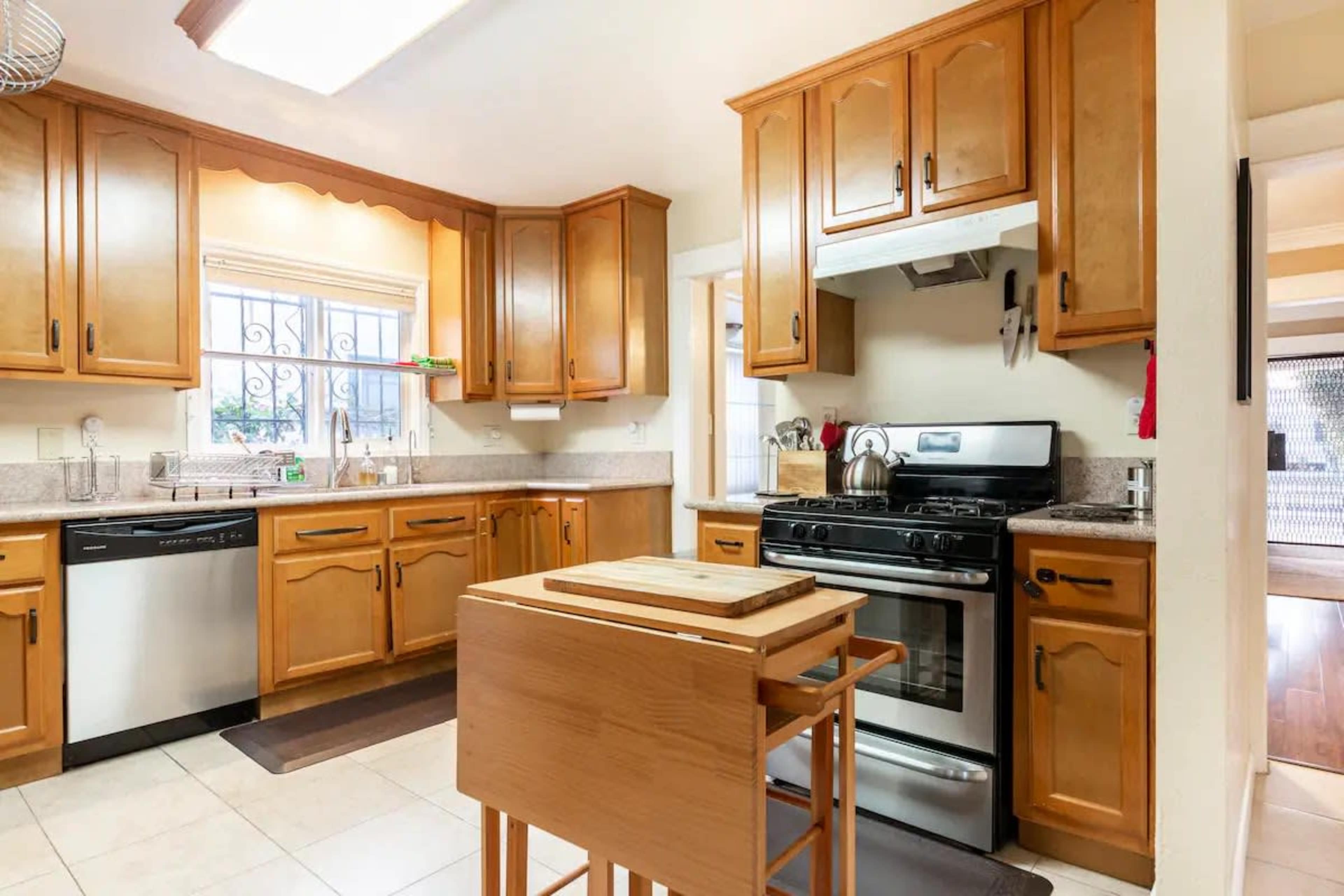 The image shows a kitchen with wooden cabinets, a stove, and an island with a cutting board on it.