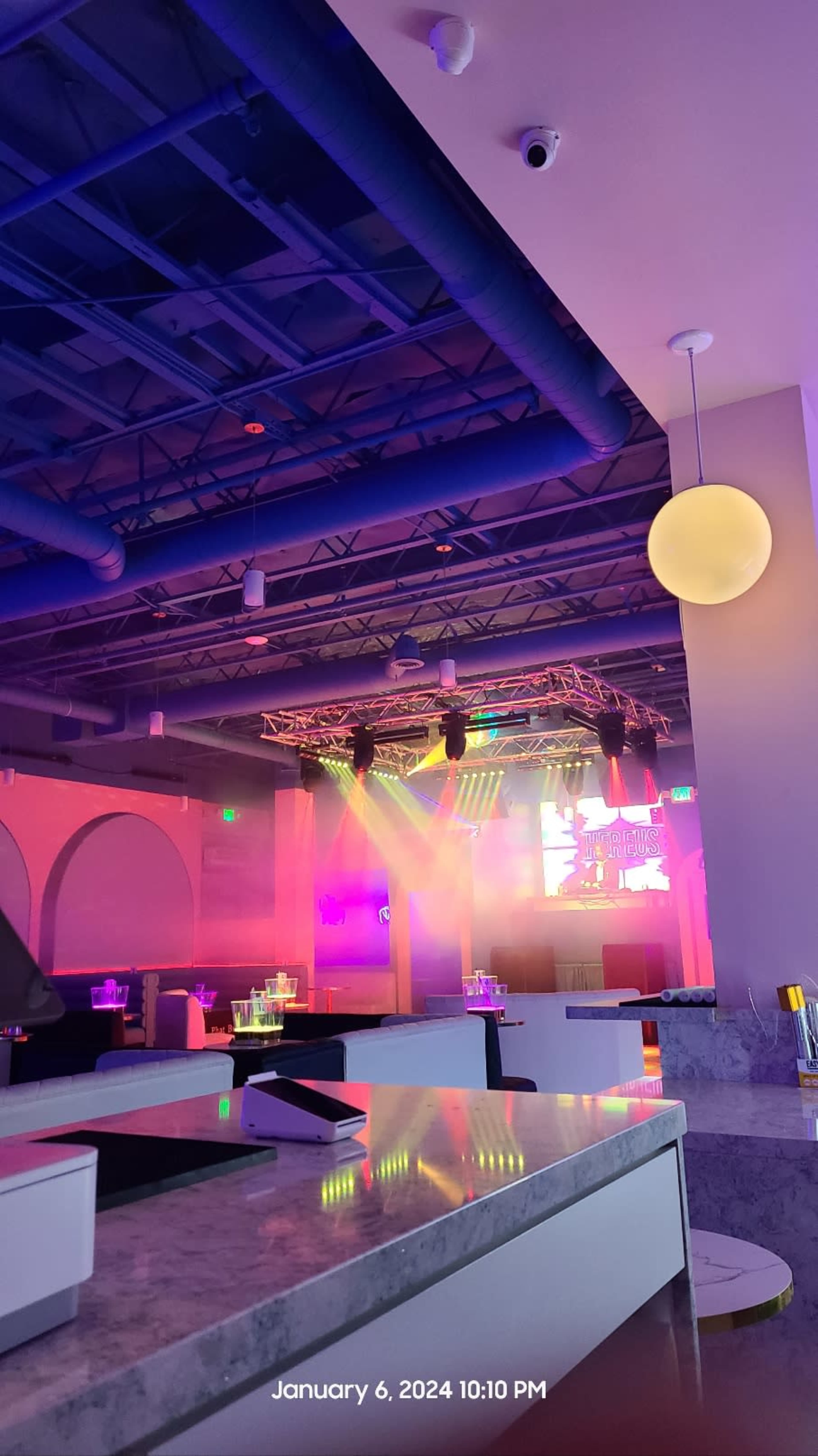 A modern restaurant interior with colorful lighting and a stage set up for performances.