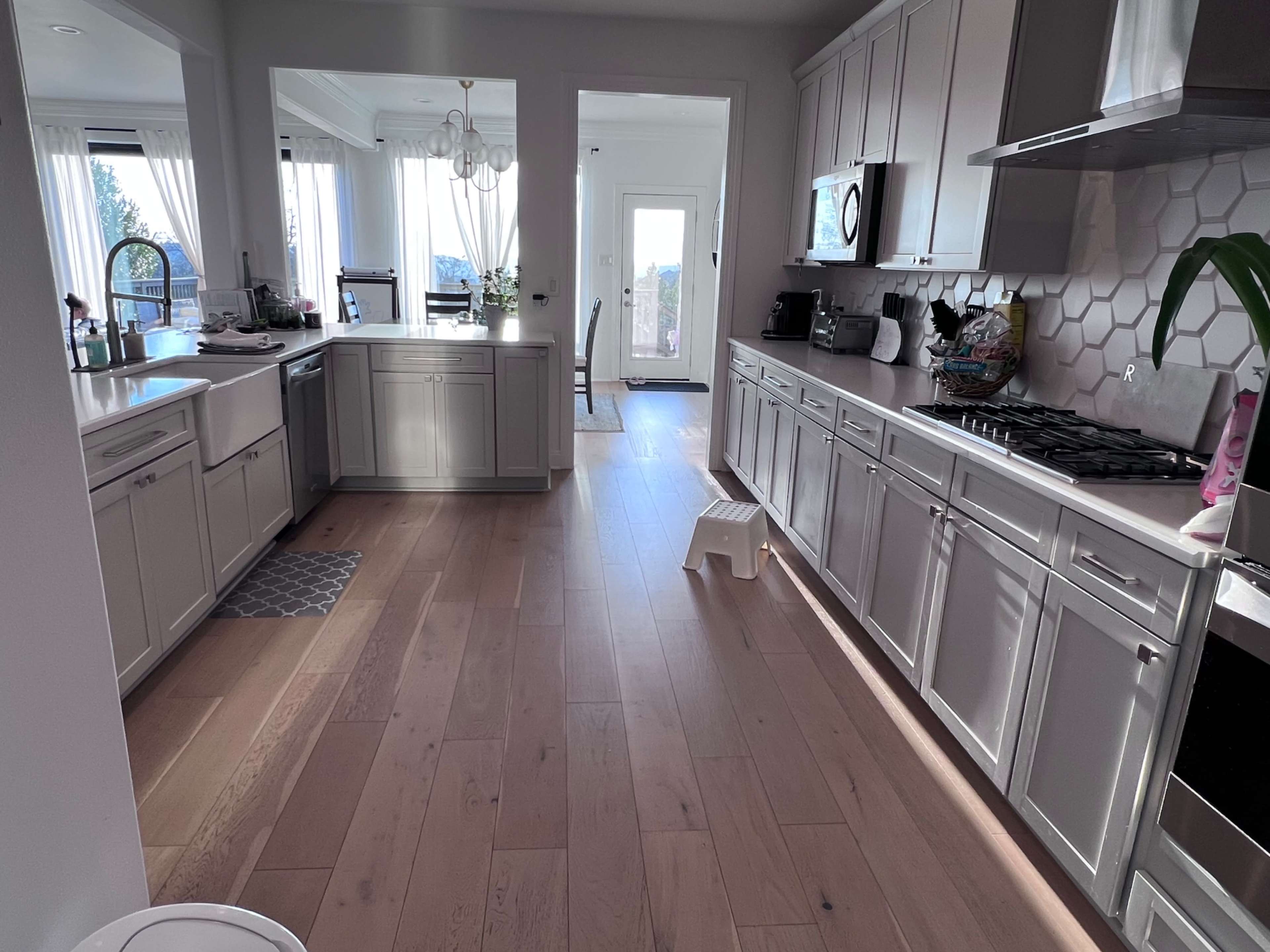 The image shows a spacious kitchen with modern cabinetry, a central island, and large windows that allow natural light to fill the area.