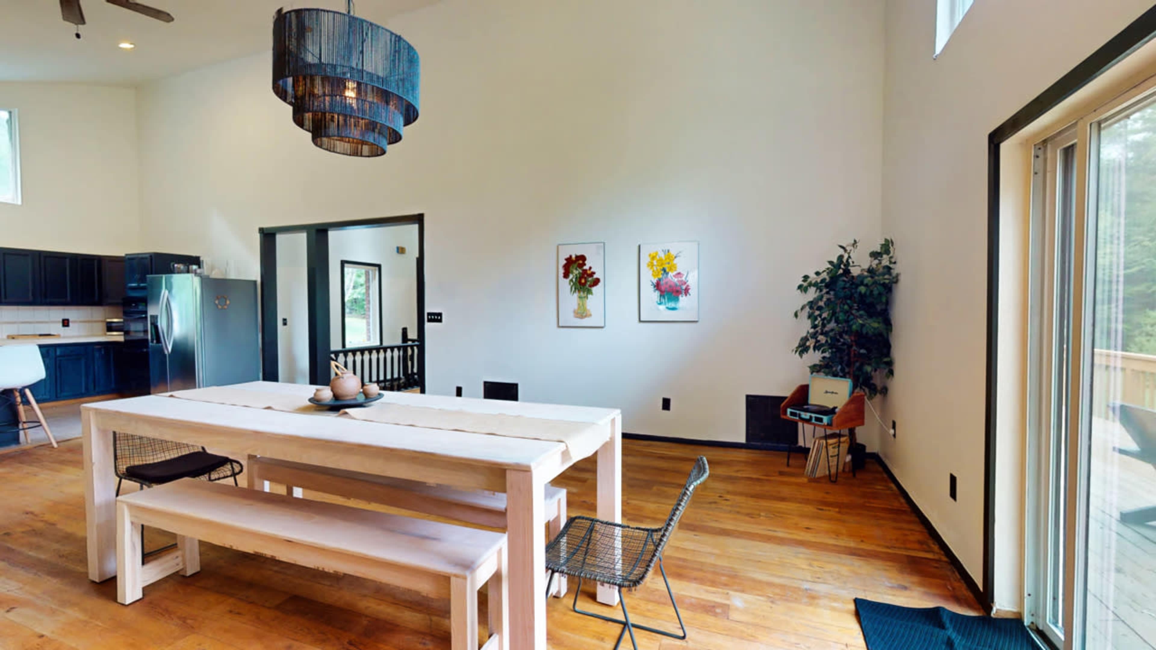 A modern dining area with a wooden table, benches, and two floral paintings on the wall.