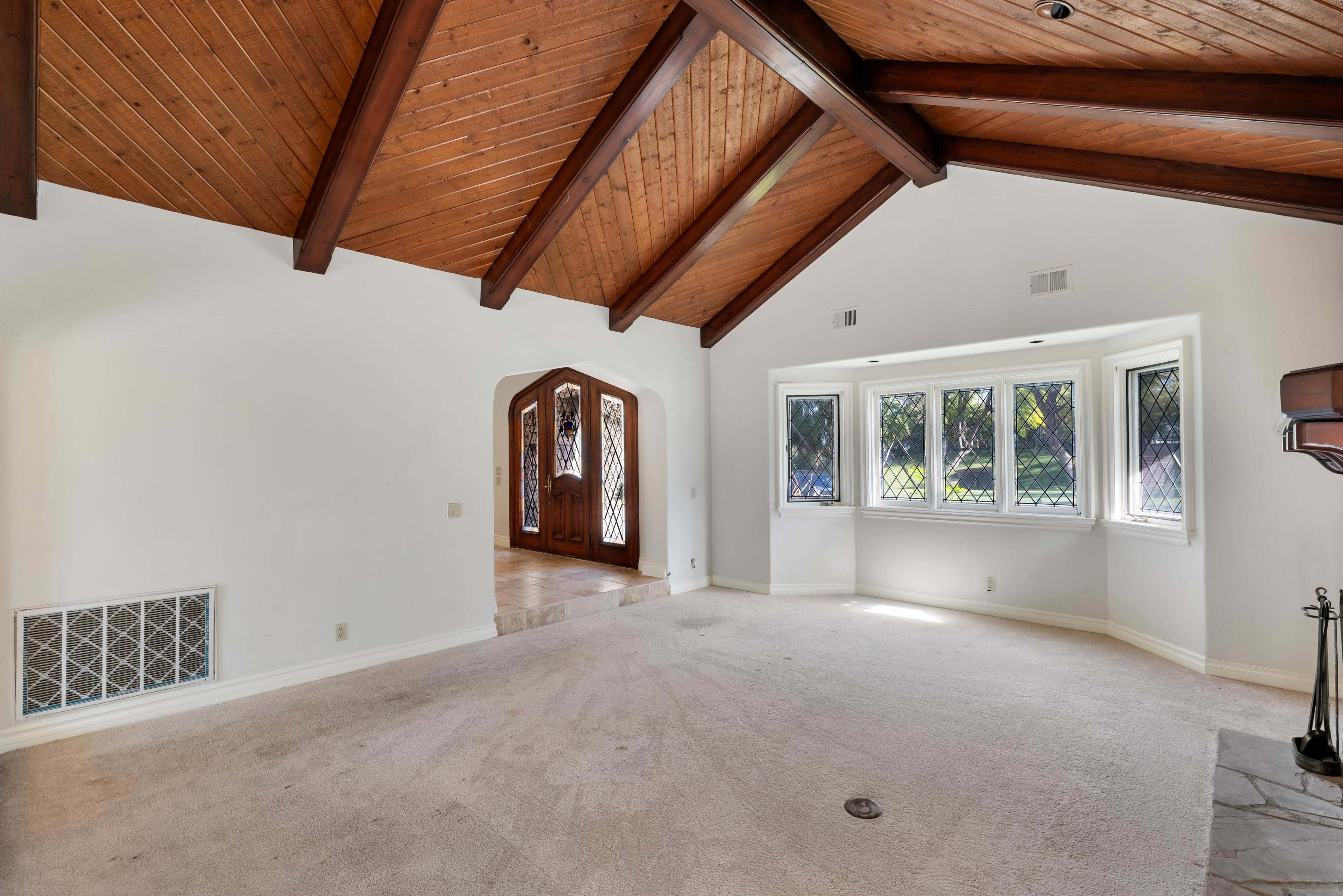 The room features a vaulted wood ceiling with exposed beams and is connected to an arched doorway leading to another area.