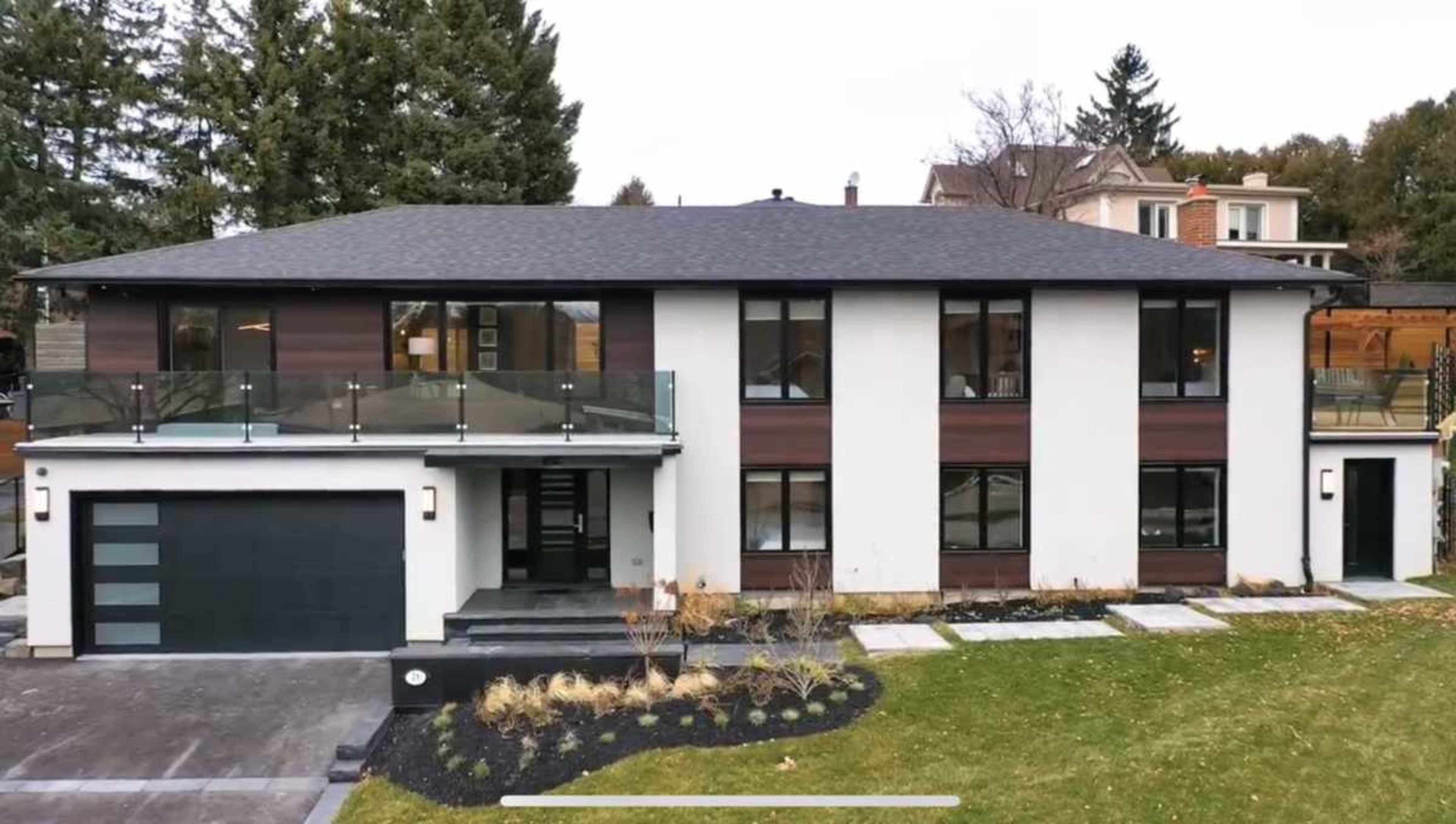 The image shows a modern two-story house with a dark roof, white and wooden exterior walls, and a landscaped front yard with stone pathways and a garage.
