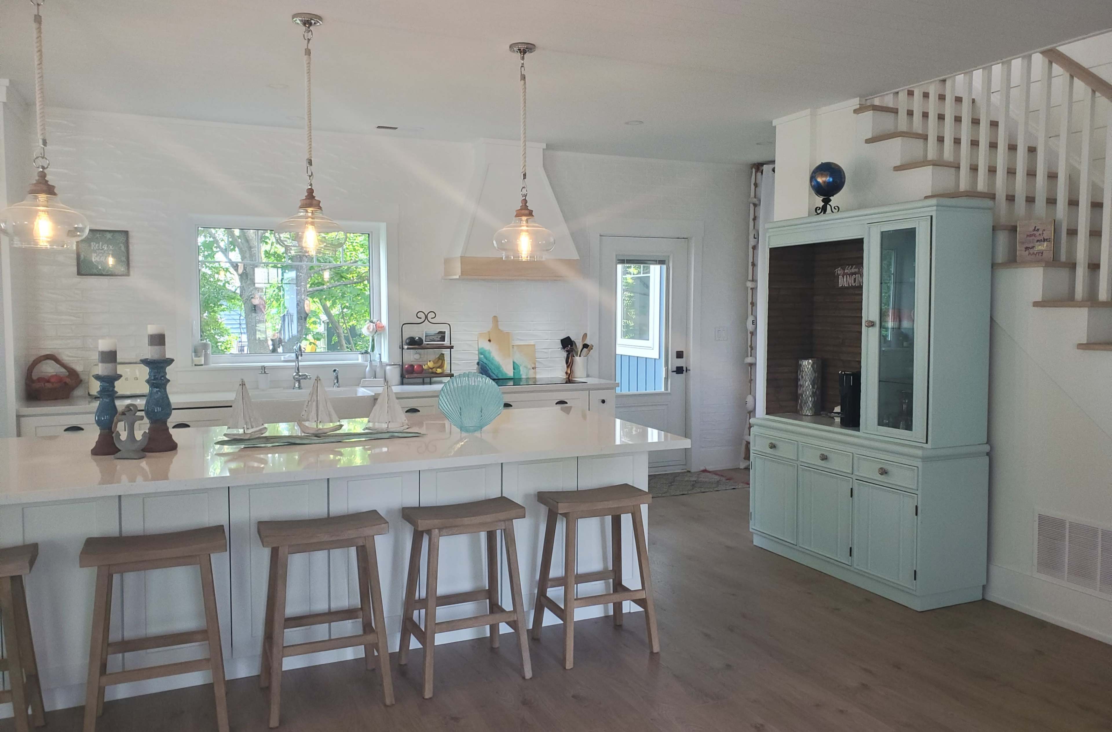 A modern kitchen equipped with a large island, barstools, and a mix of wood and white cabinetry.