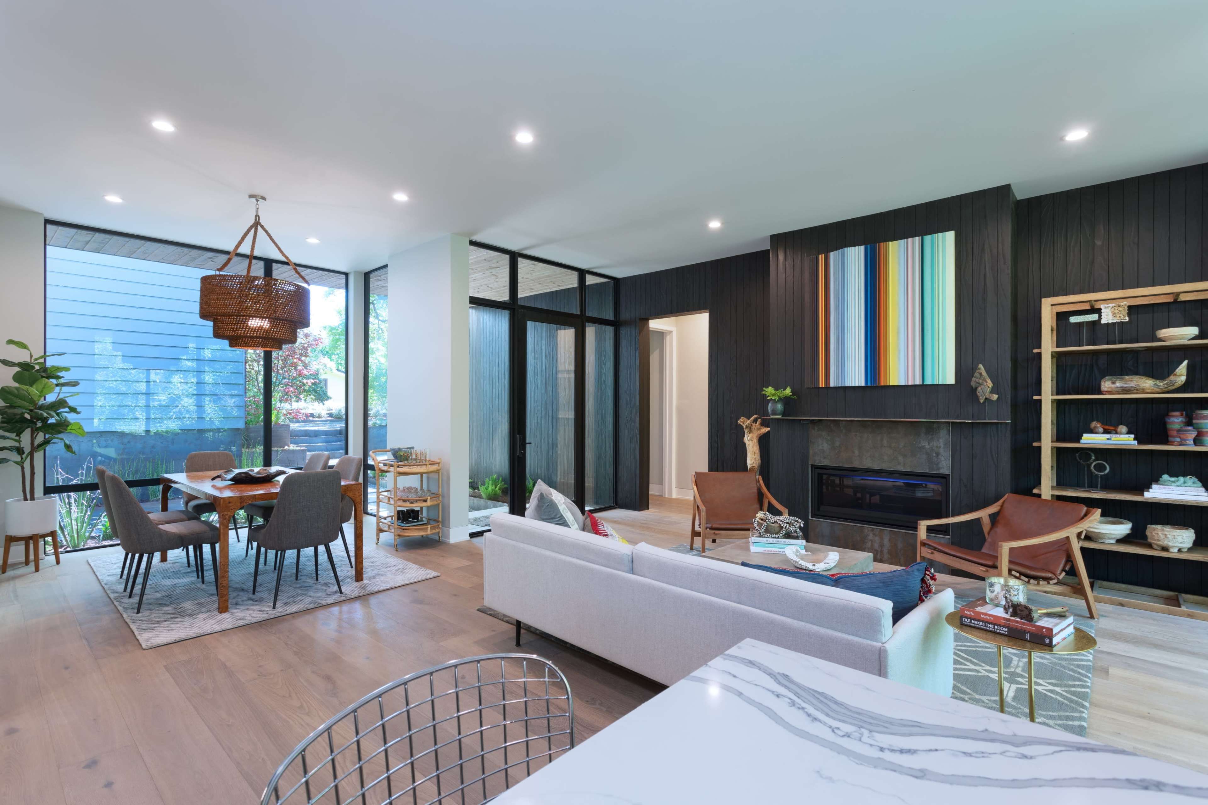 A modern living space with a dining area, a cozy seating area, and large windows allowing natural light to enter.