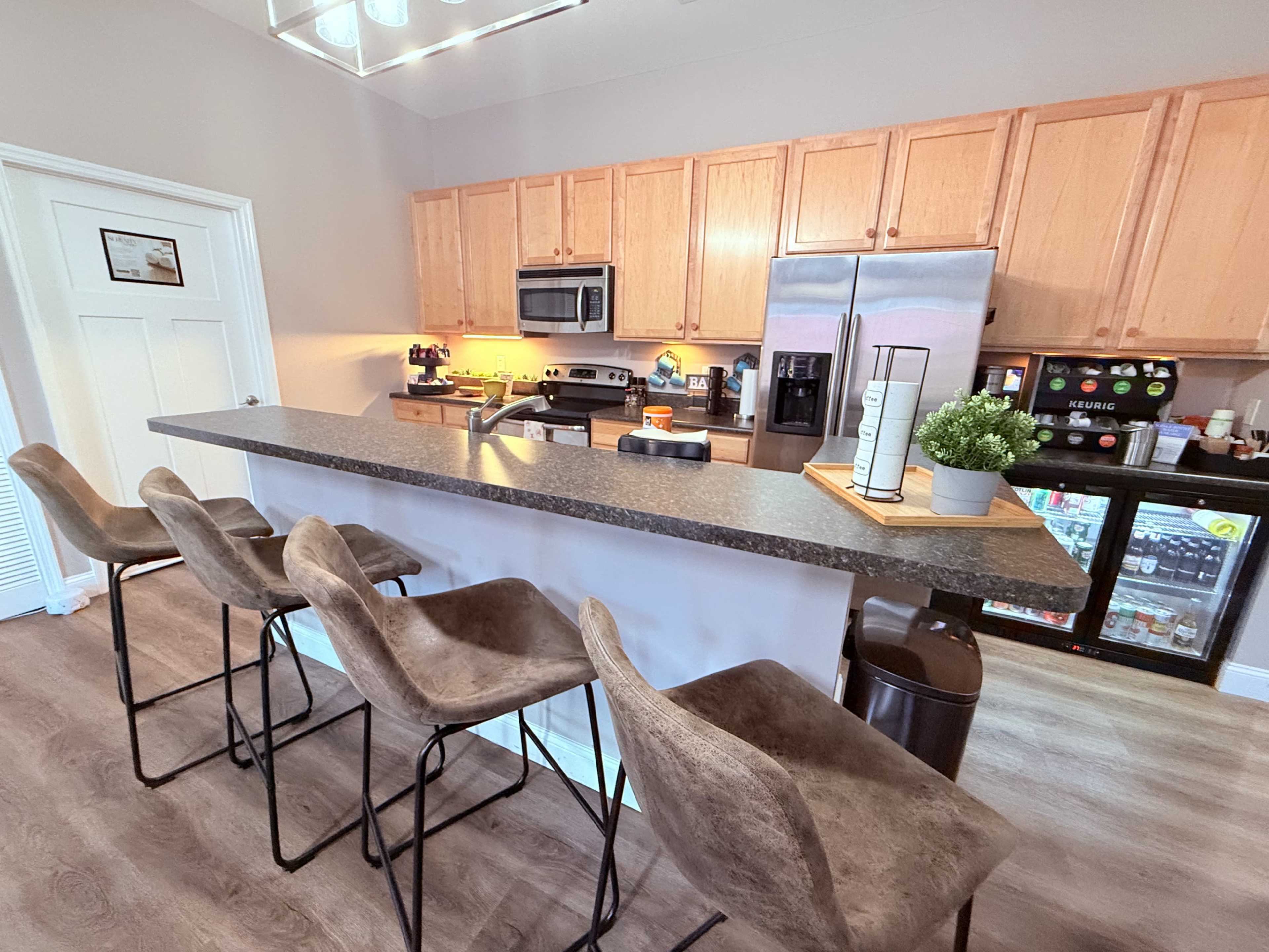 A modern kitchen features wooden cabinets, a large island with bar seating, and stainless steel appliances.