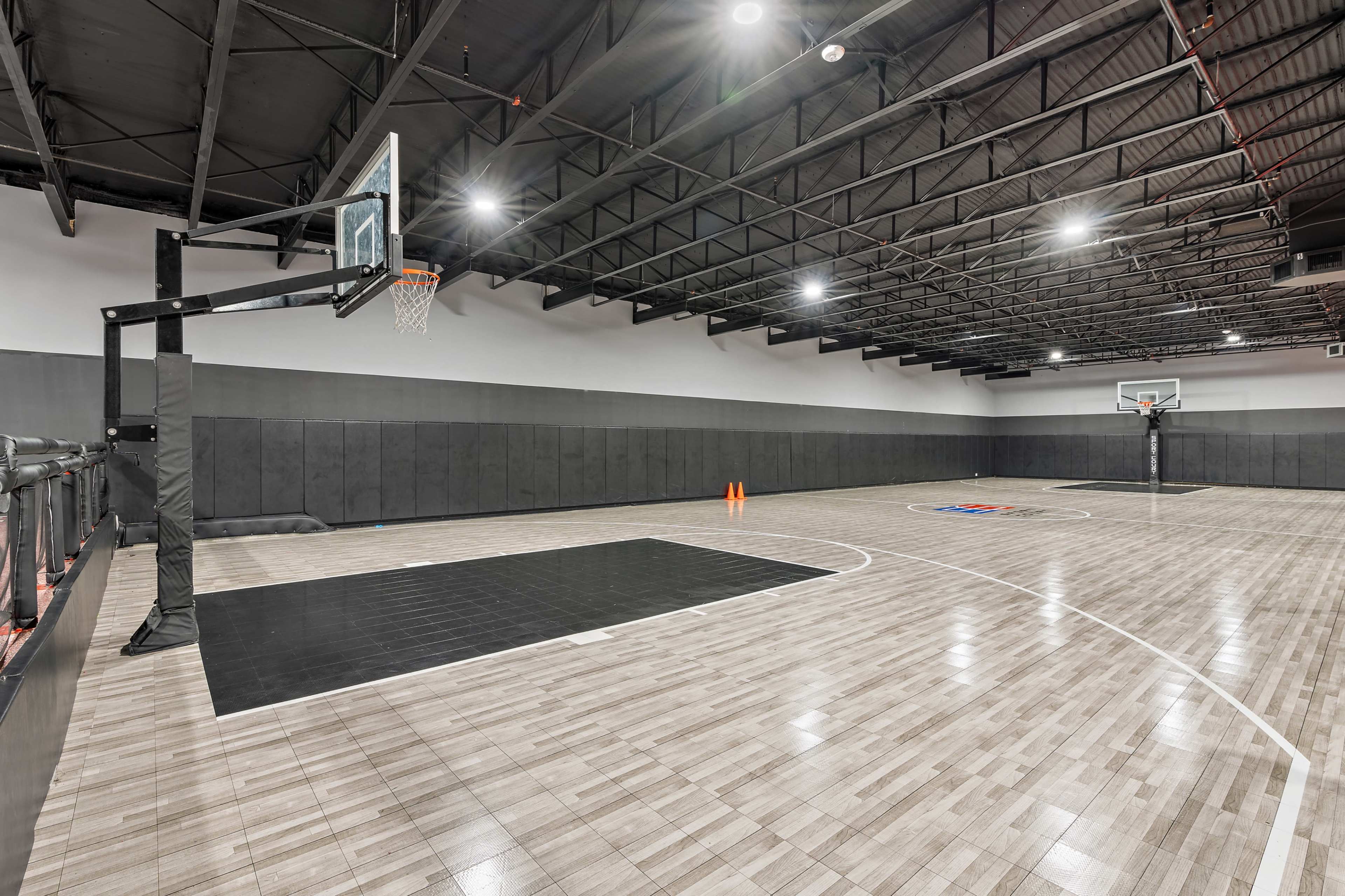 An indoor basketball court with two hoops at opposite ends and a hardwood floor.