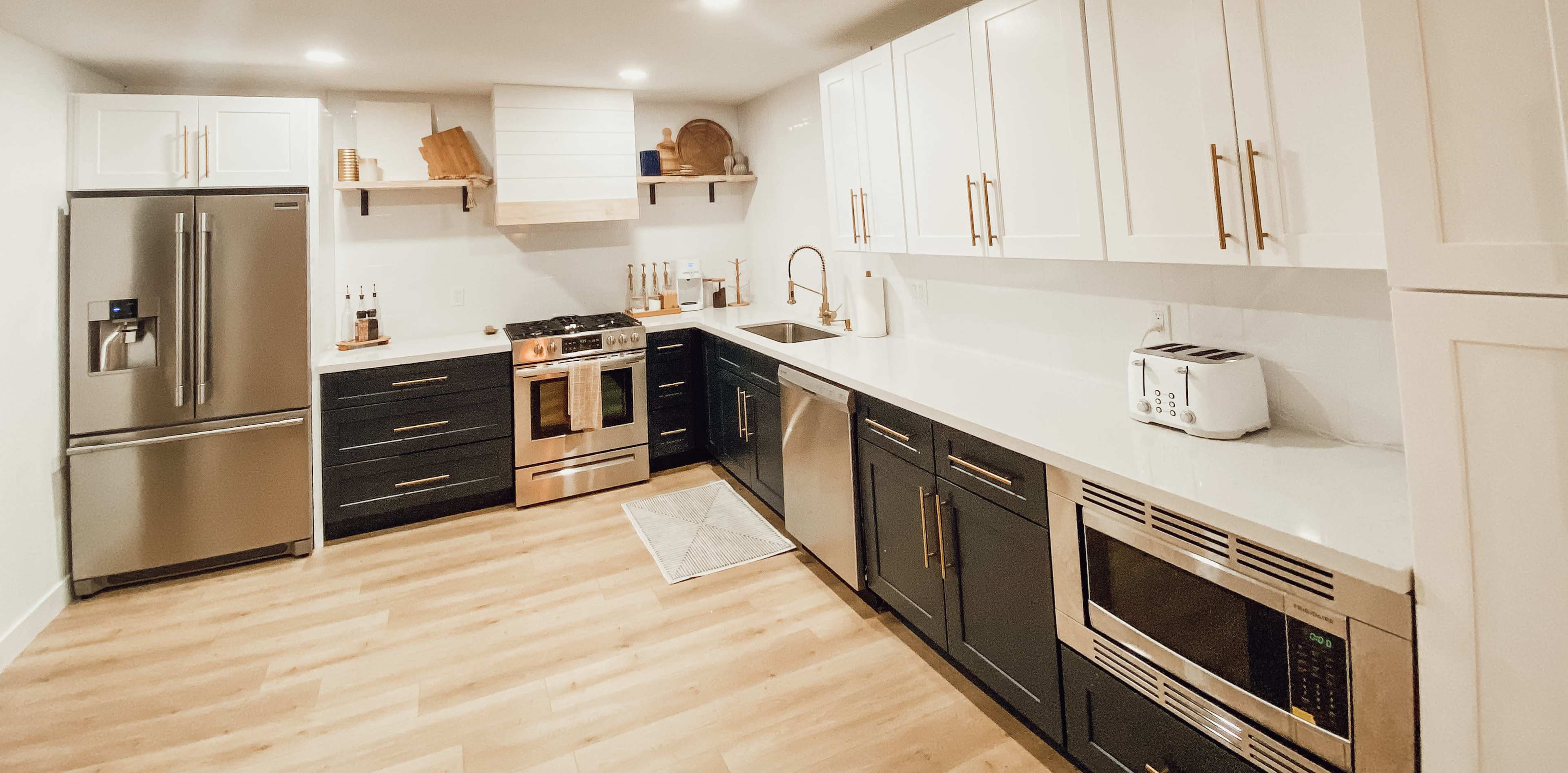 A modern kitchen features stainless steel appliances, white cabinetry, and gray countertops with a wooden accent decor.