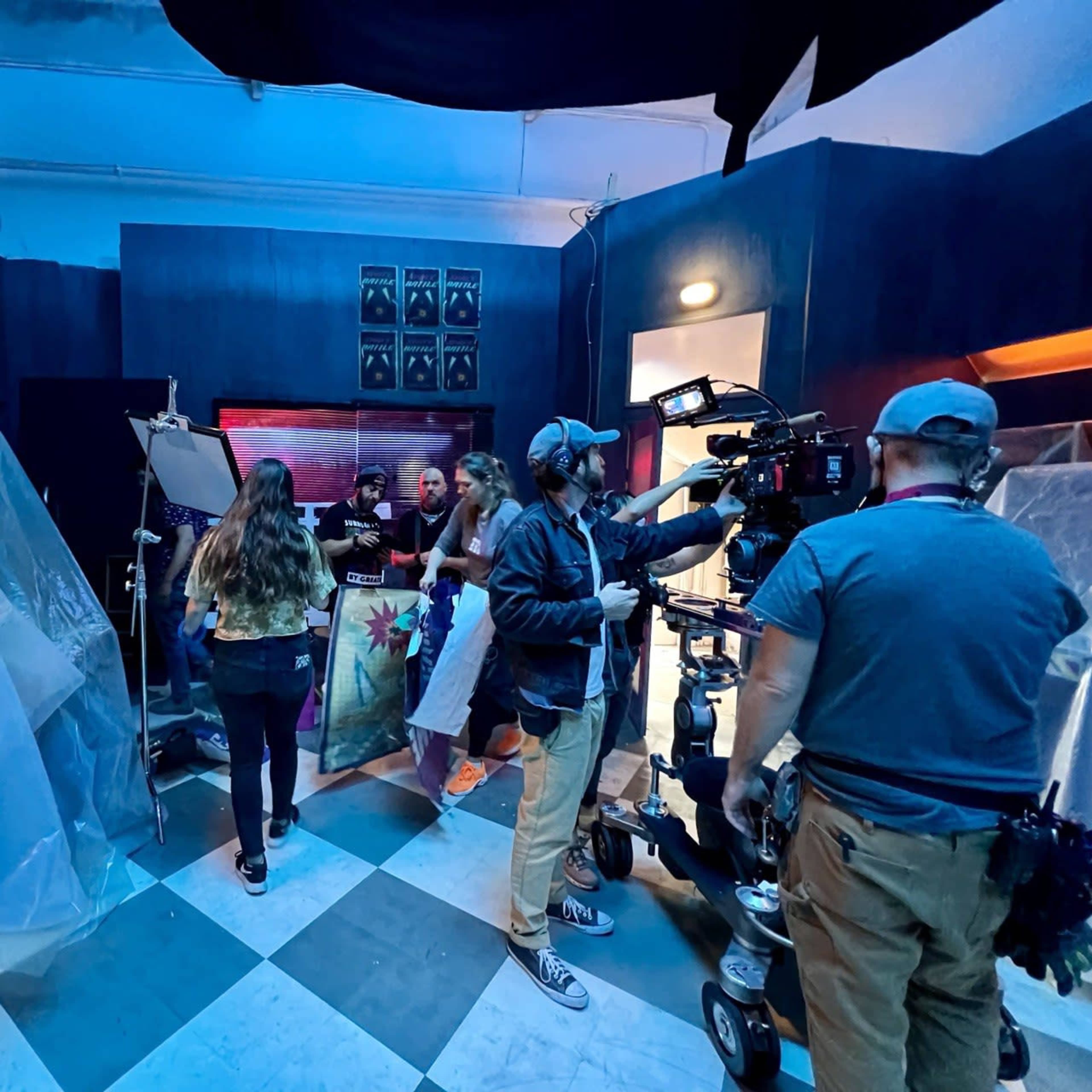 A film crew is setting up equipment in a dimly lit studio, preparing for a production scene.