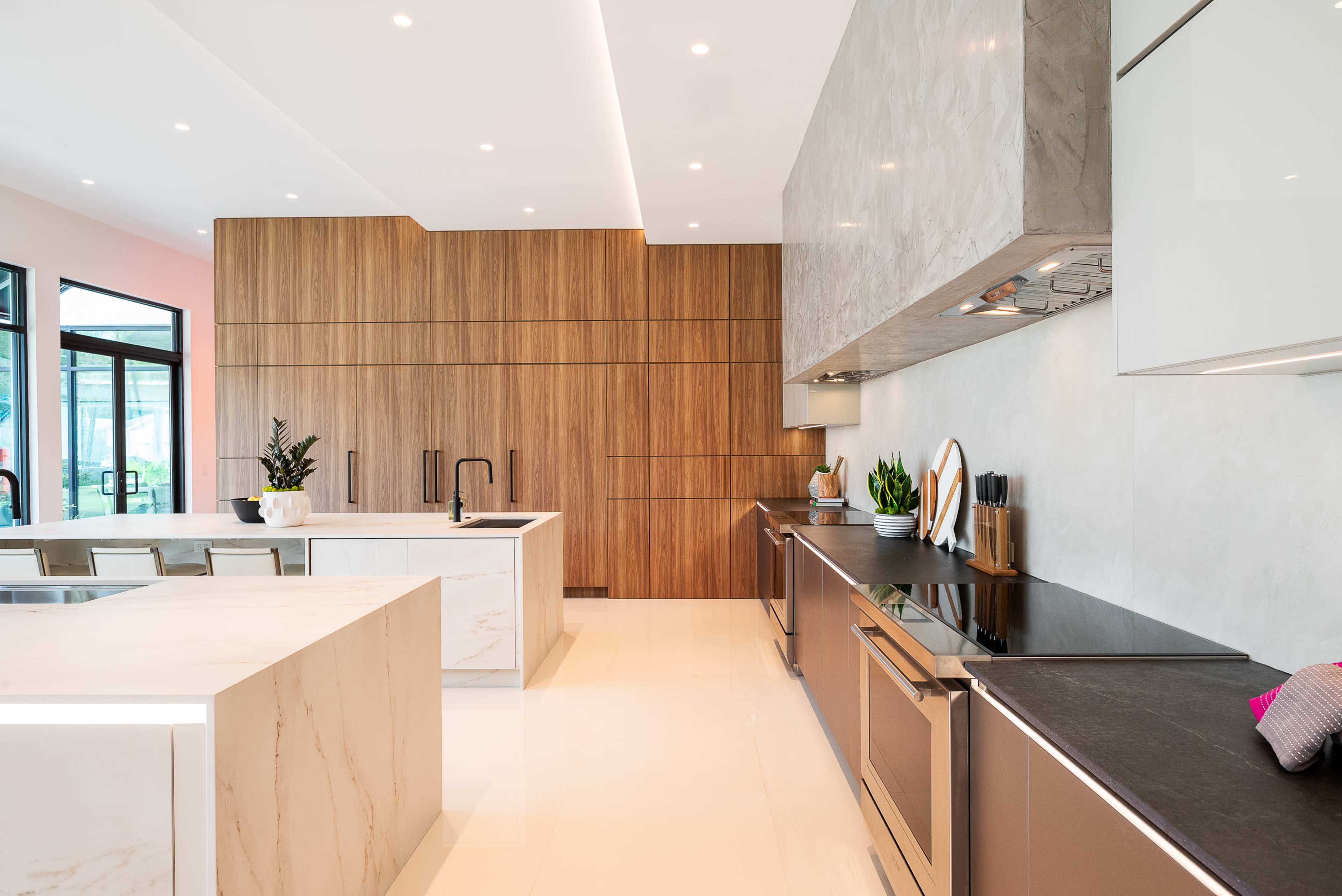 The kitchen features a sleek design with a large island, wooden cabinetry, and modern stainless steel appliances.