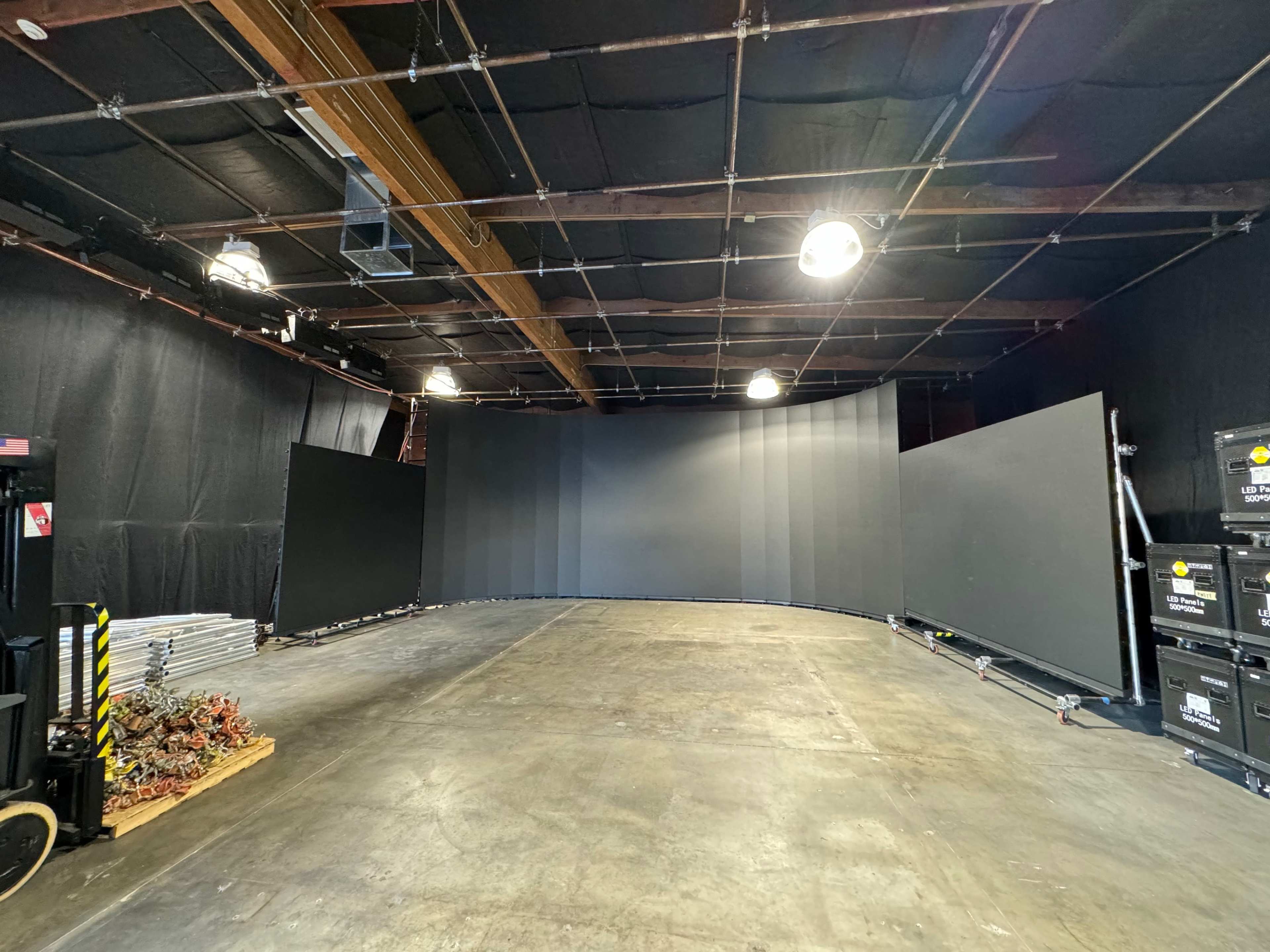 A large studio space with a curved backdrop, surrounded by black curtains and various equipment along the sides.