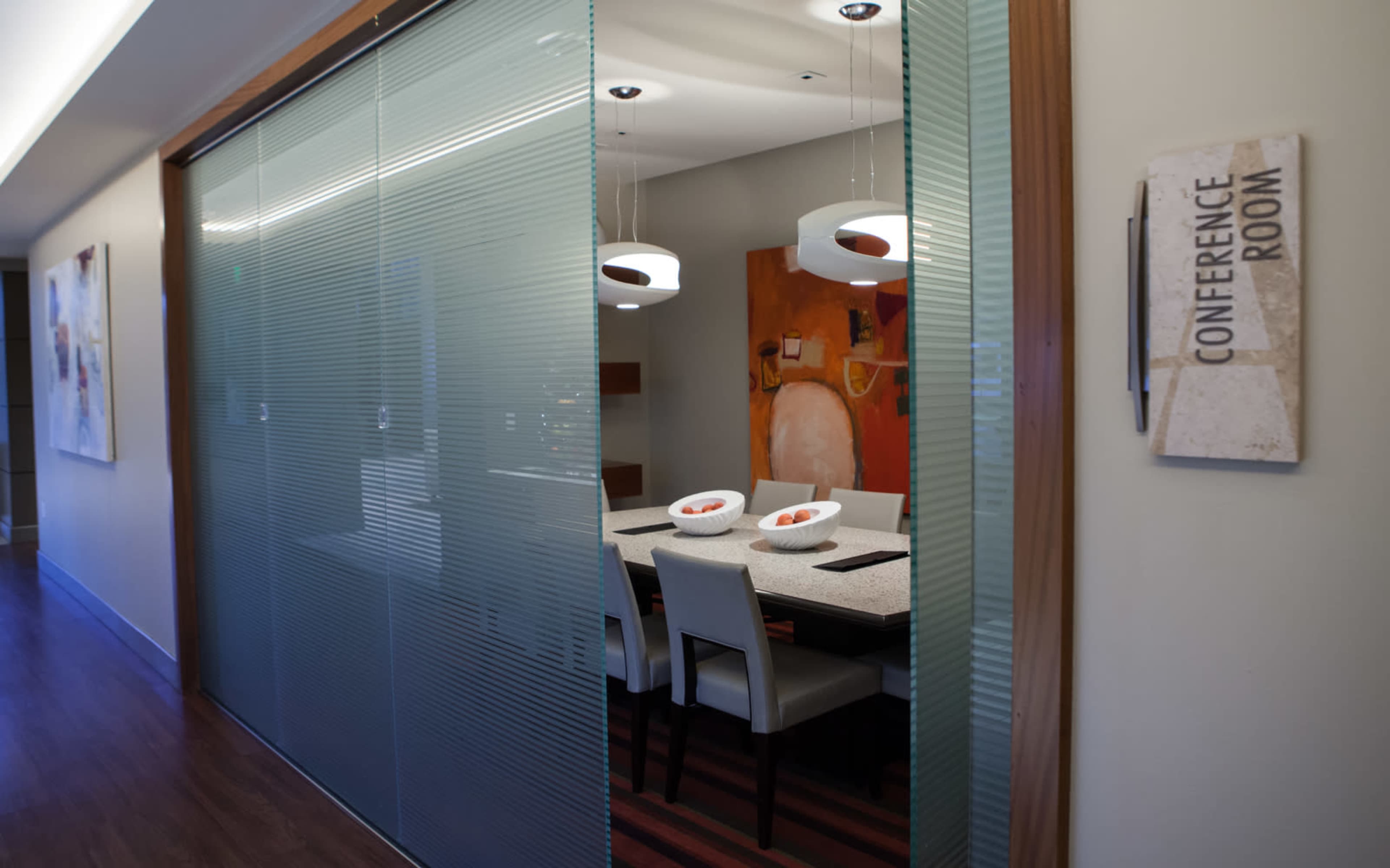 A conference room with a table set for meetings is seen through a glass door, with a sign labeled "CONFERENCE ROOM" on the wall.