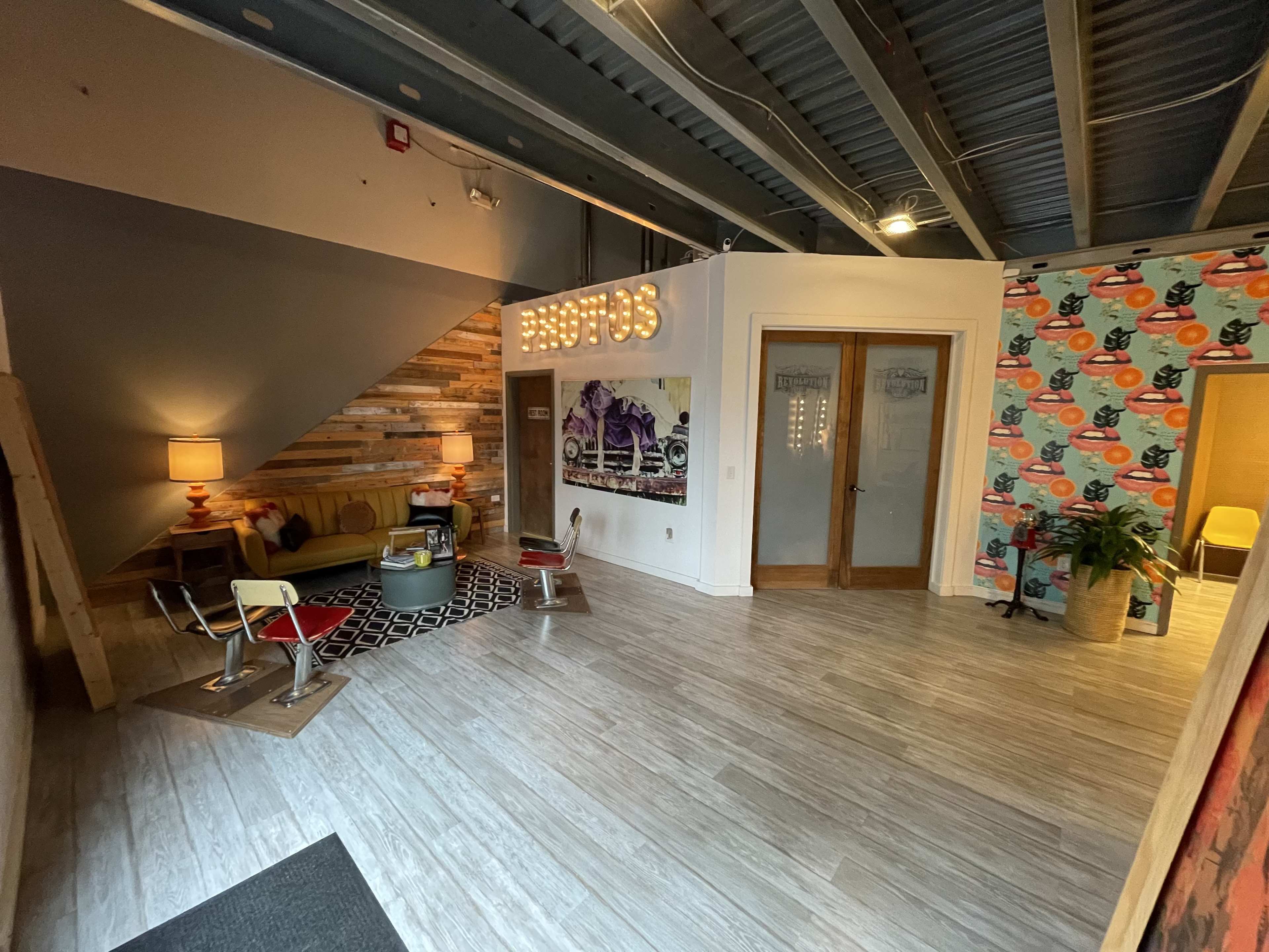 A modern reception area with wooden walls, a sofa, a lamp, and a wall decorated with colorful circular patterns.