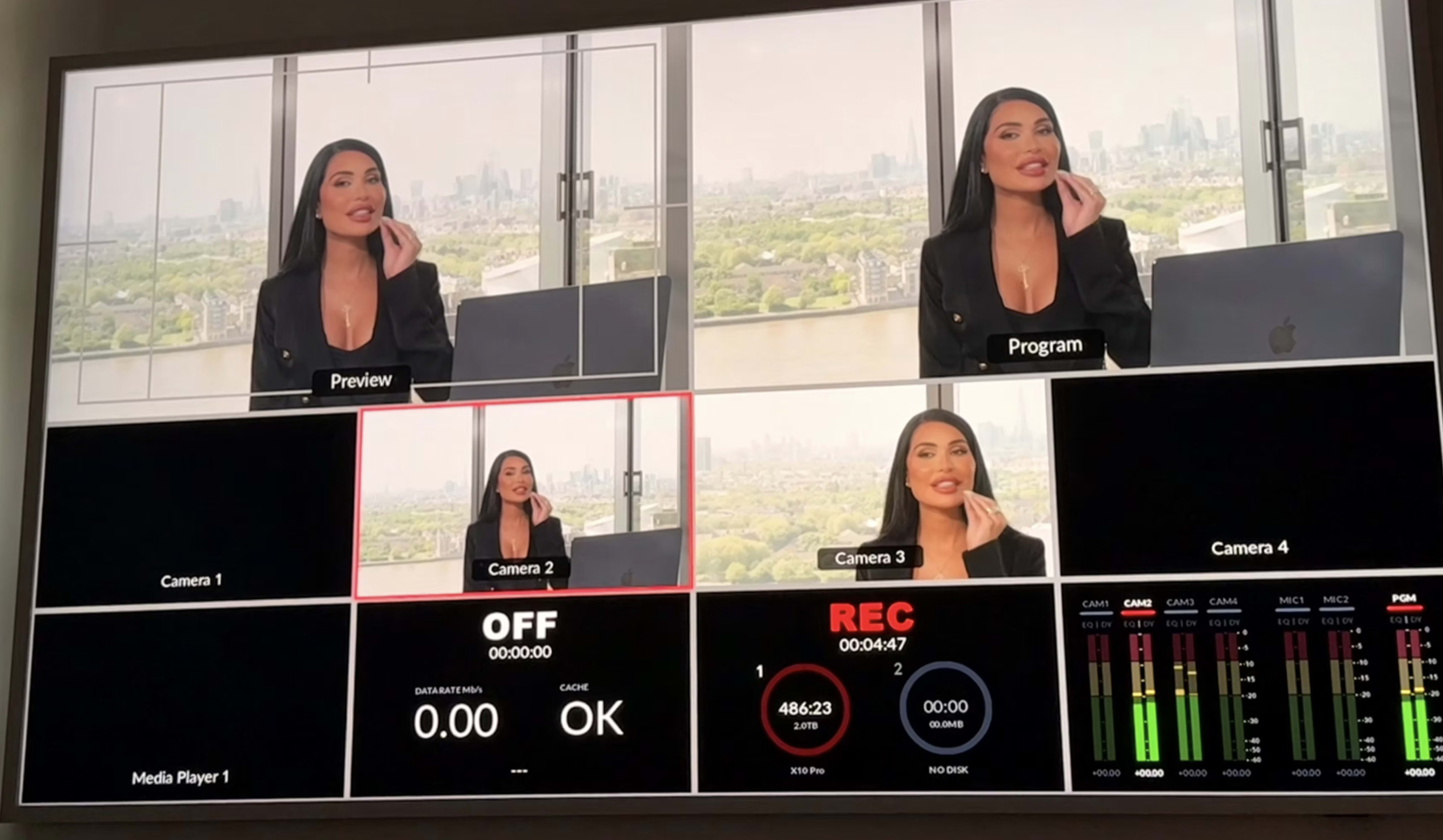 The image shows a multi-camera monitoring display featuring a woman in front of a large window, with various camera feeds and status indicators visible on the screen.