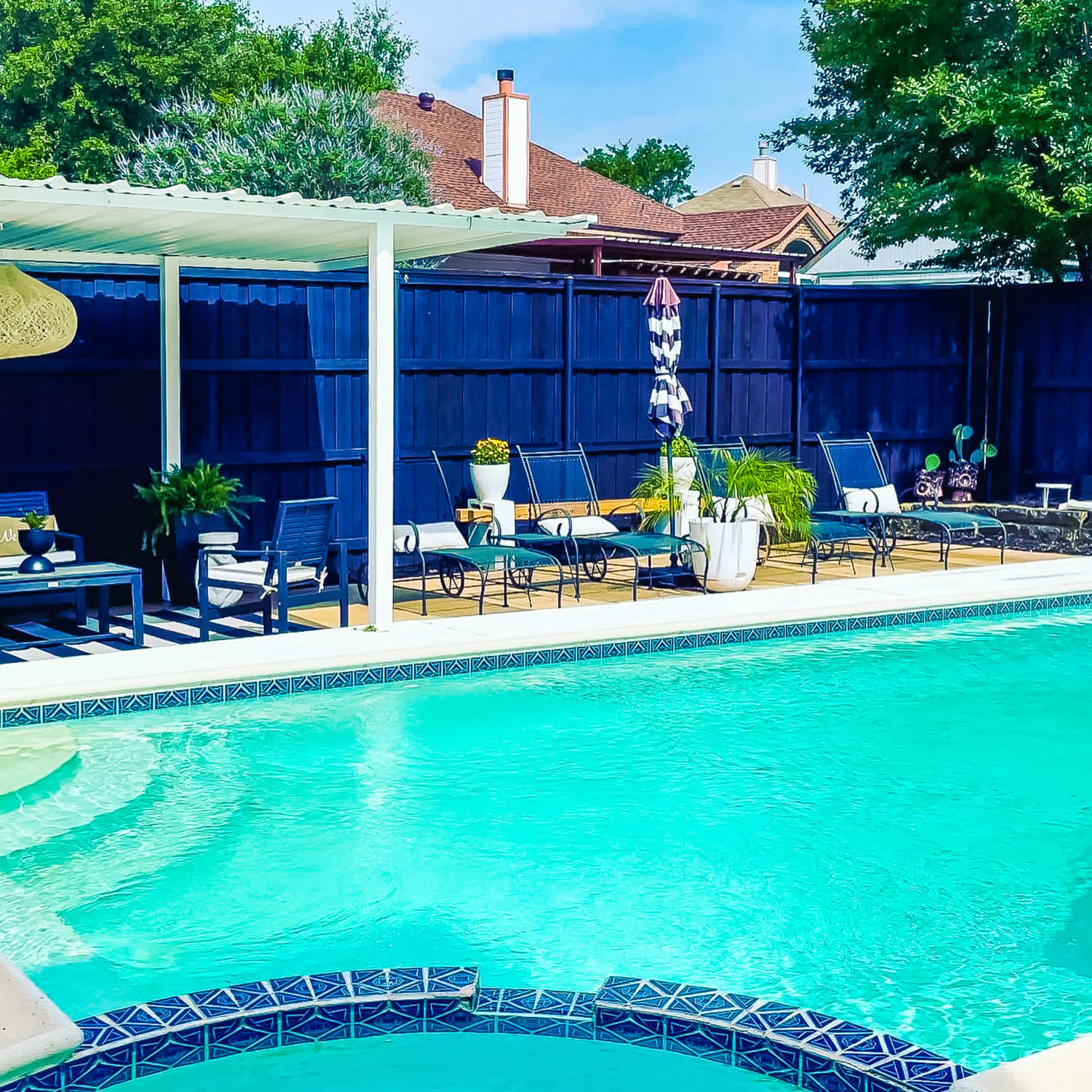 The image shows a backyard pool area with lounge chairs, a table, and a shaded pergola beside a clear blue swimming pool.