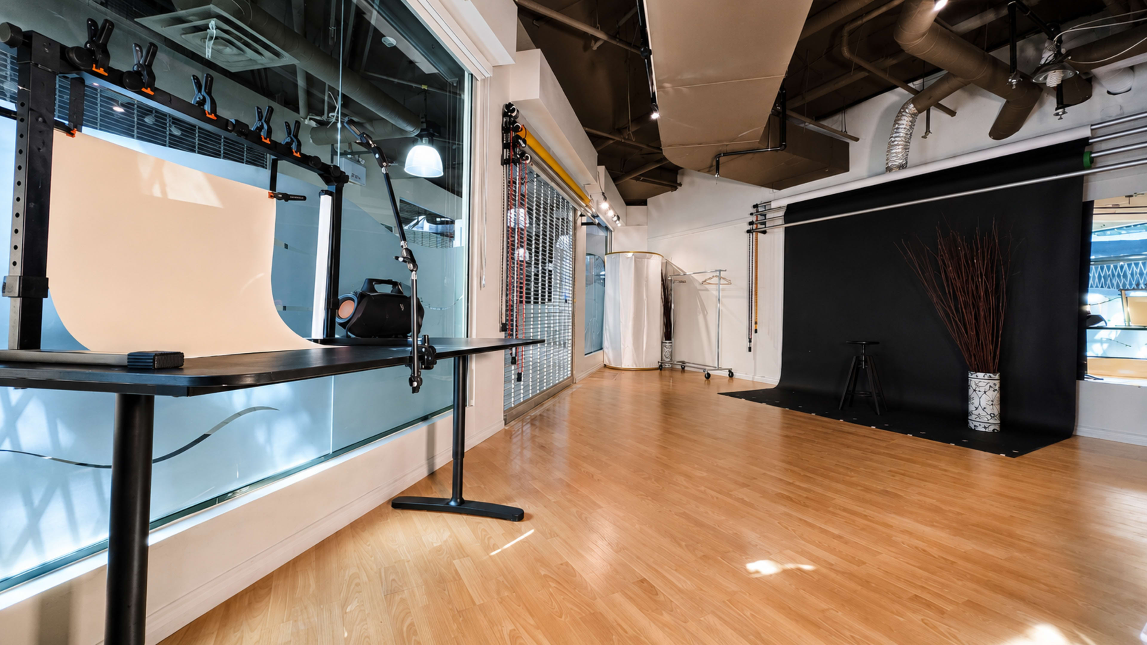 The image shows a spacious photography studio featuring a white backdrop on one side and a black backdrop on the other, with equipment and props arranged for a photoshoot.
