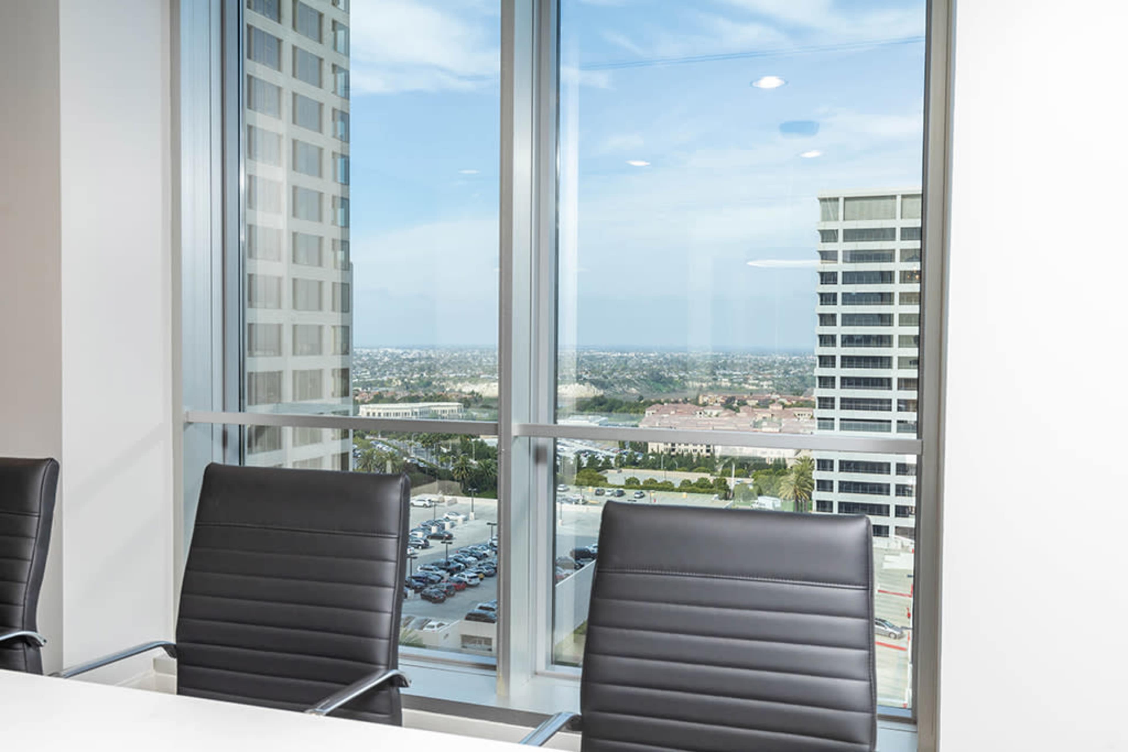 The image shows an empty conference room with black chairs and large windows overlooking a cityscape.