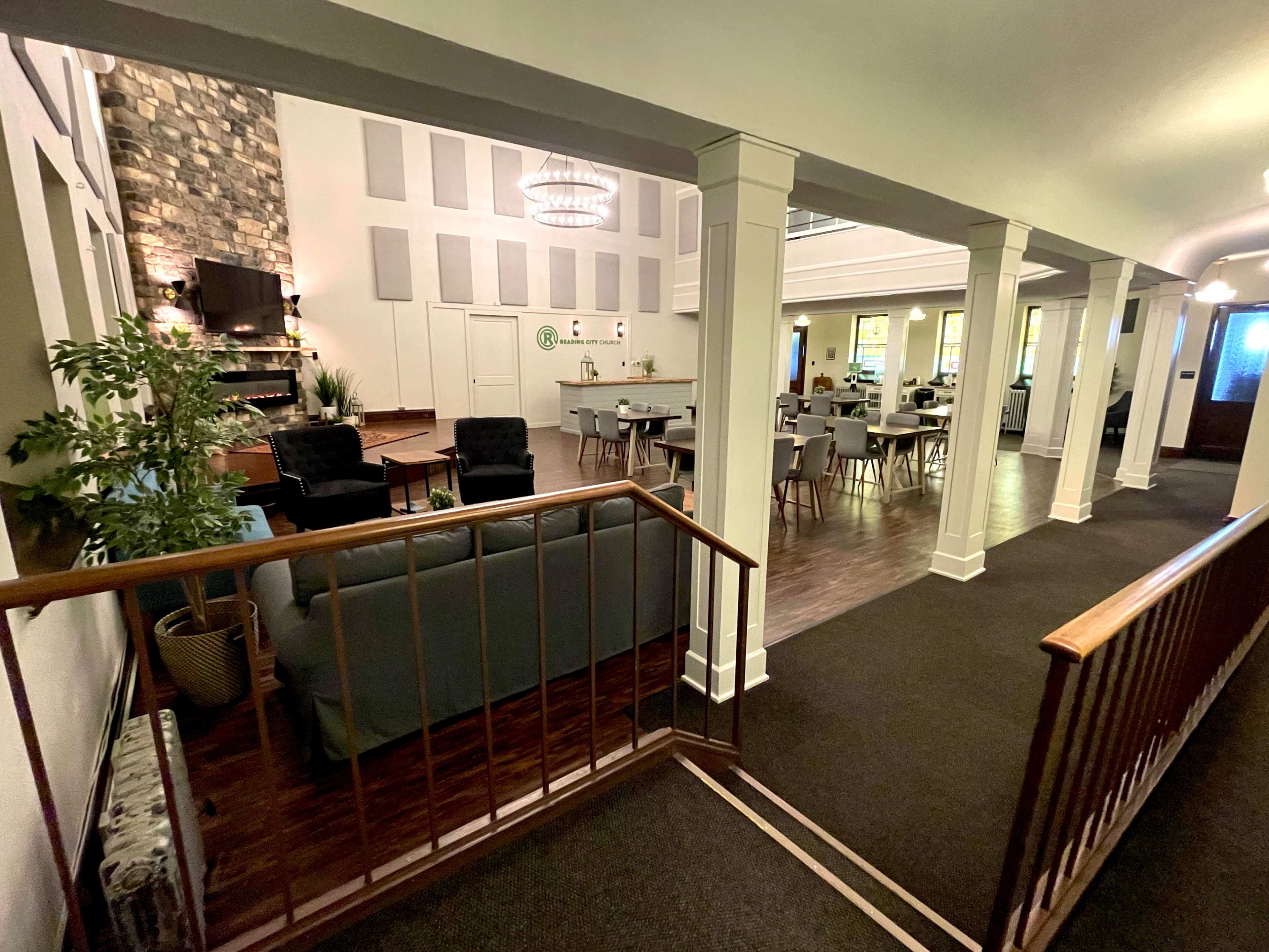 A spacious indoor area with a modern design, featuring seating arrangements, a large dining space, and tall windows.
