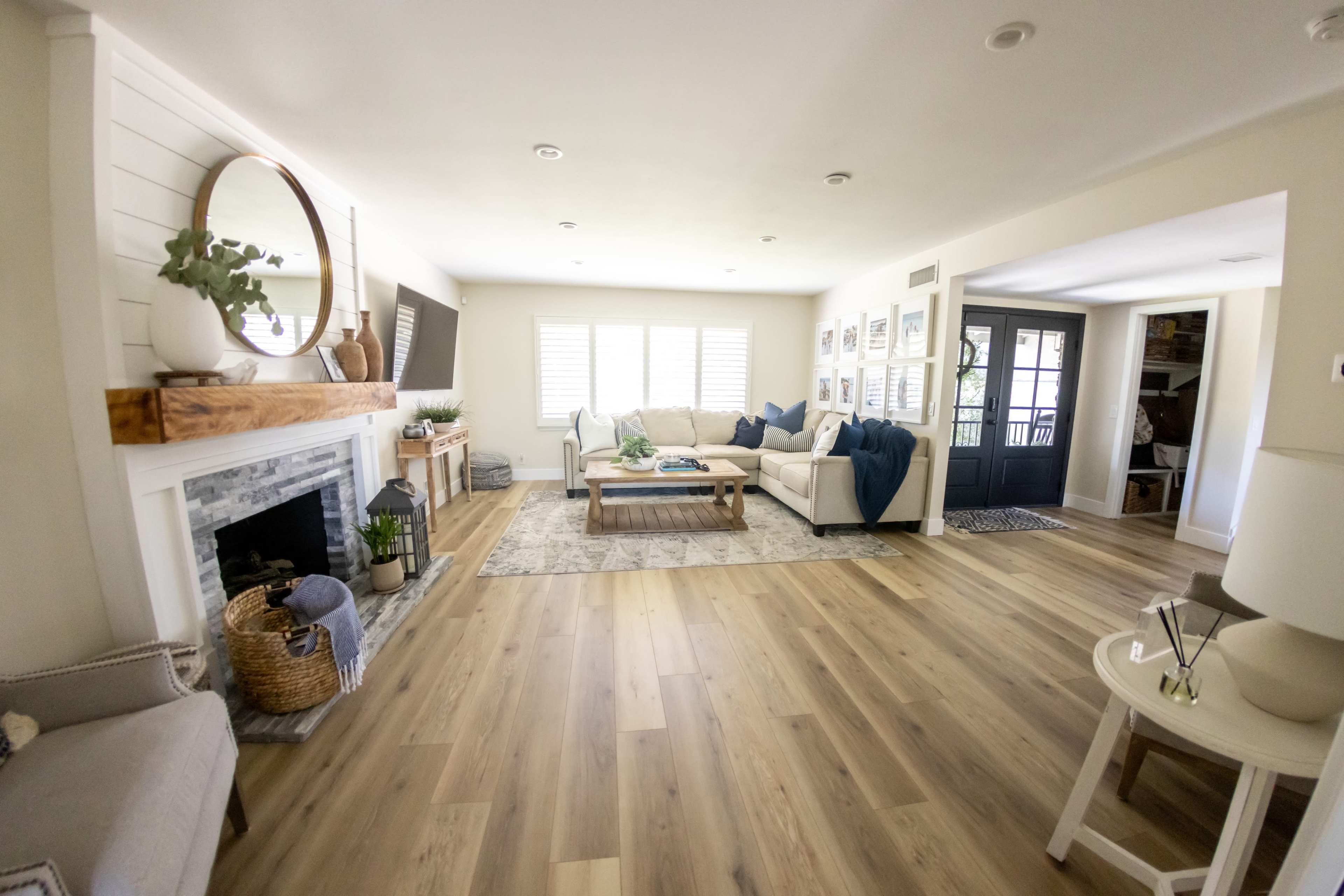 The image shows a spacious living room with a fireplace, seating area, and large windows allowing natural light.