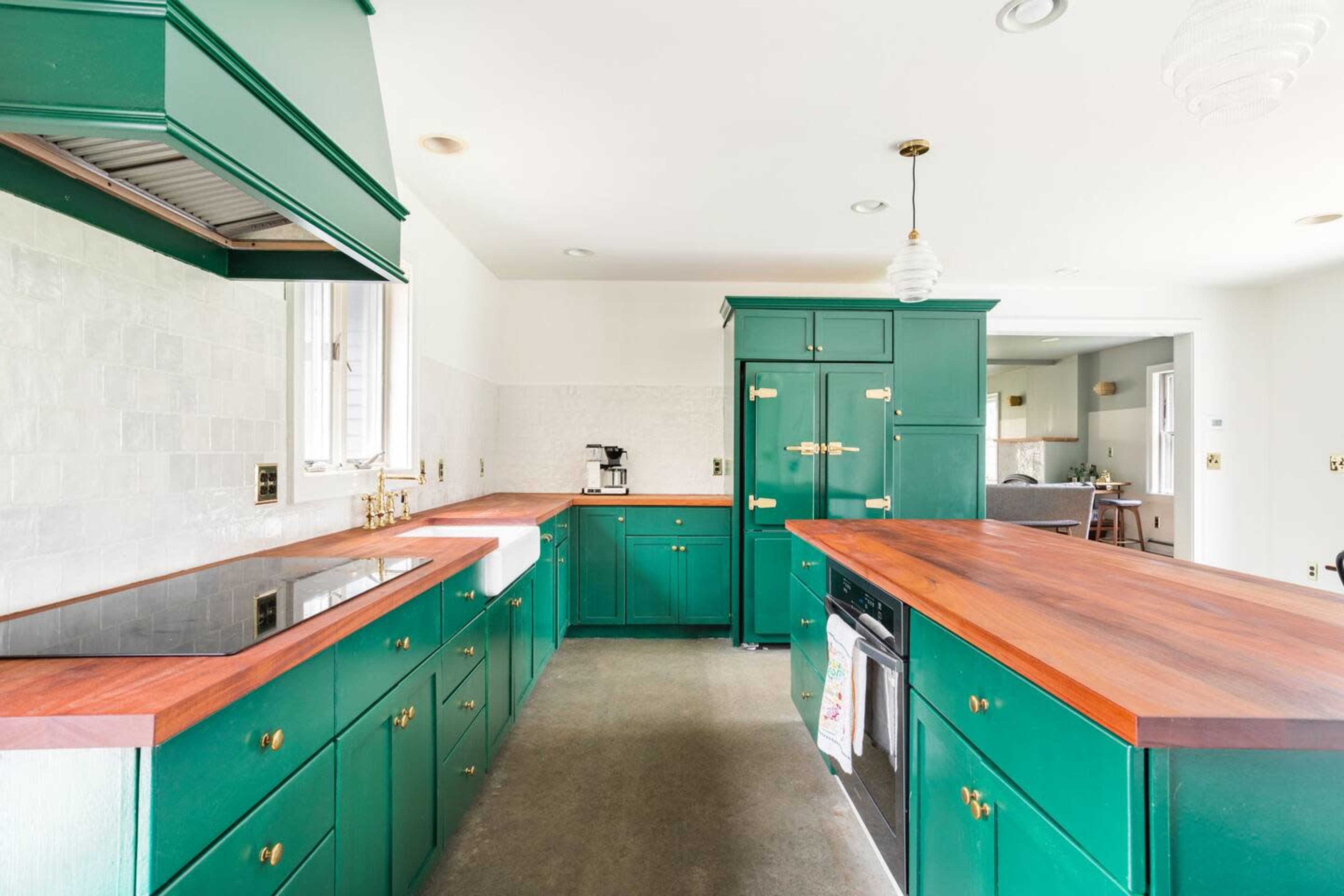 The kitchen features green cabinetry, wooden countertops, and modern appliances with an open layout.