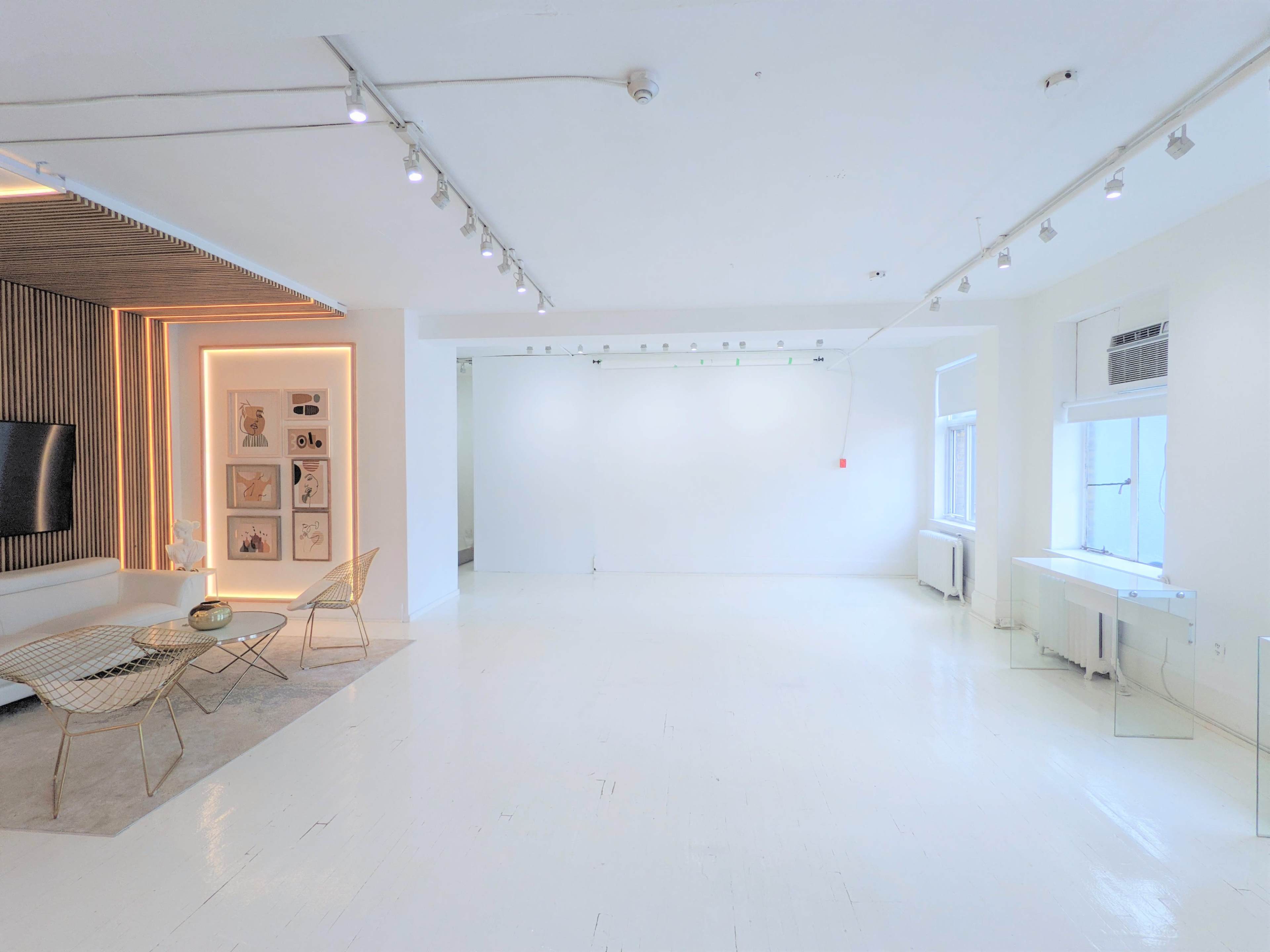 A spacious, well-lit room with white walls, polished floors, and simple furniture.