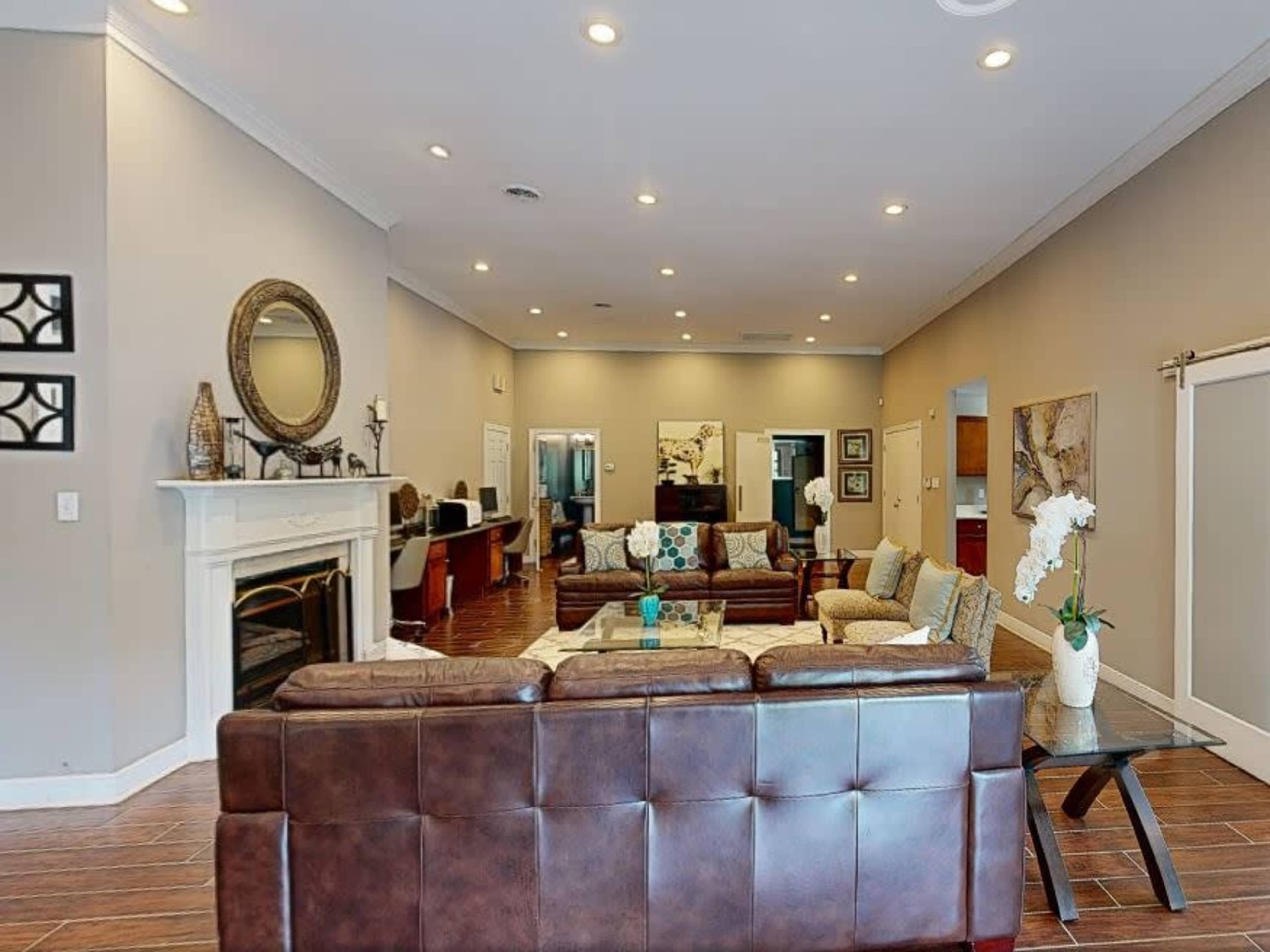A spacious living room furnished with multiple seating arrangements, a fireplace, and a large mirror on the wall.