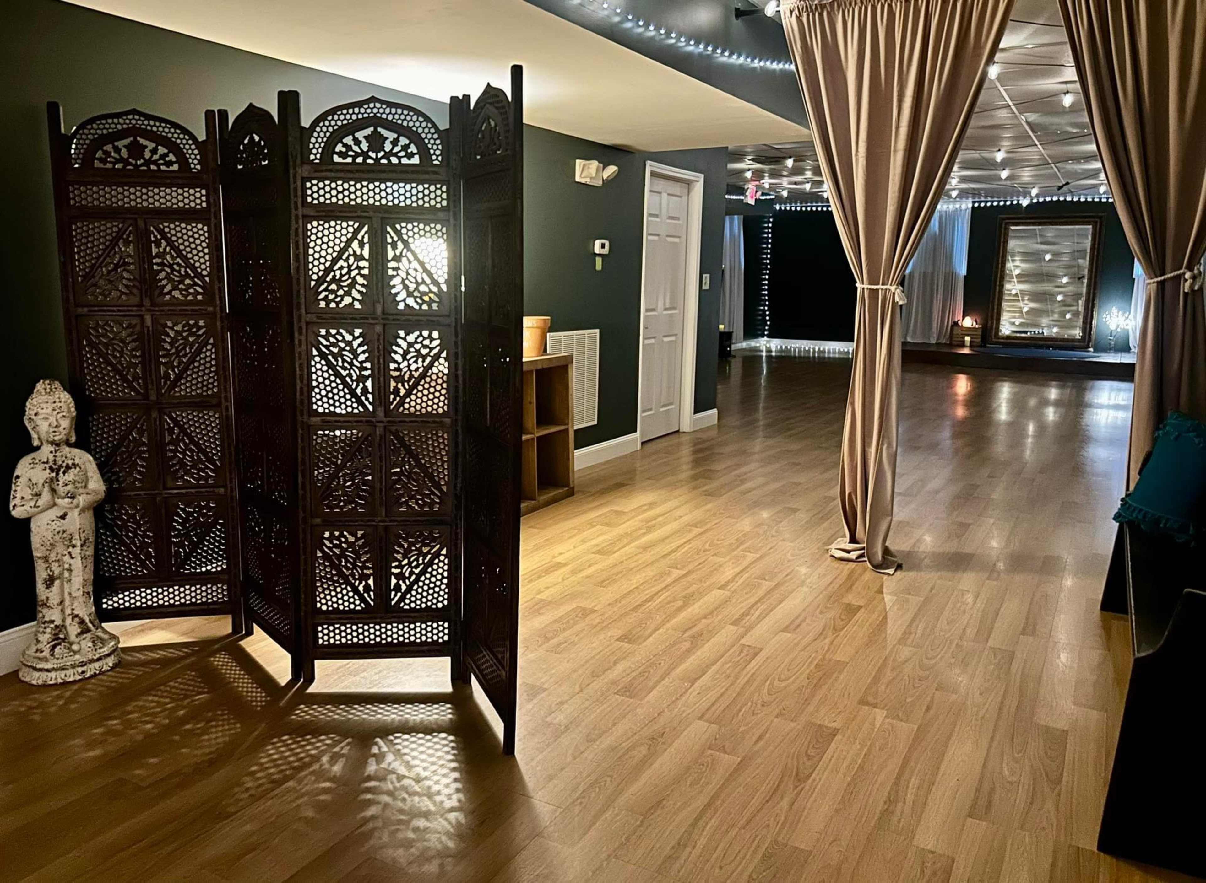 A tranquil interior space with wooden flooring, a decorative folding screen, and soft lighting, creating an inviting atmosphere.