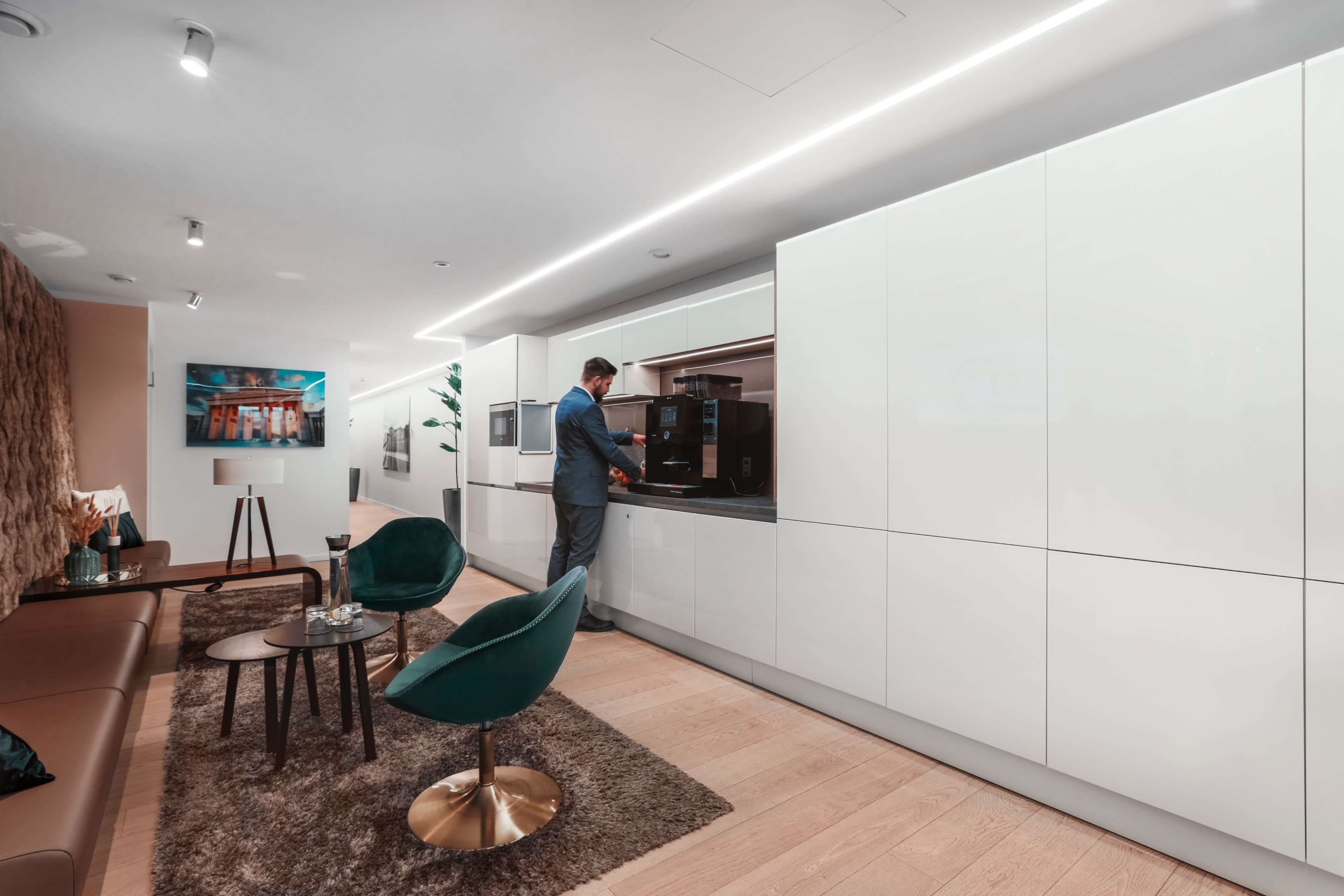A man prepares a beverage at a modern kitchen counter in a stylish, well-lit living space.