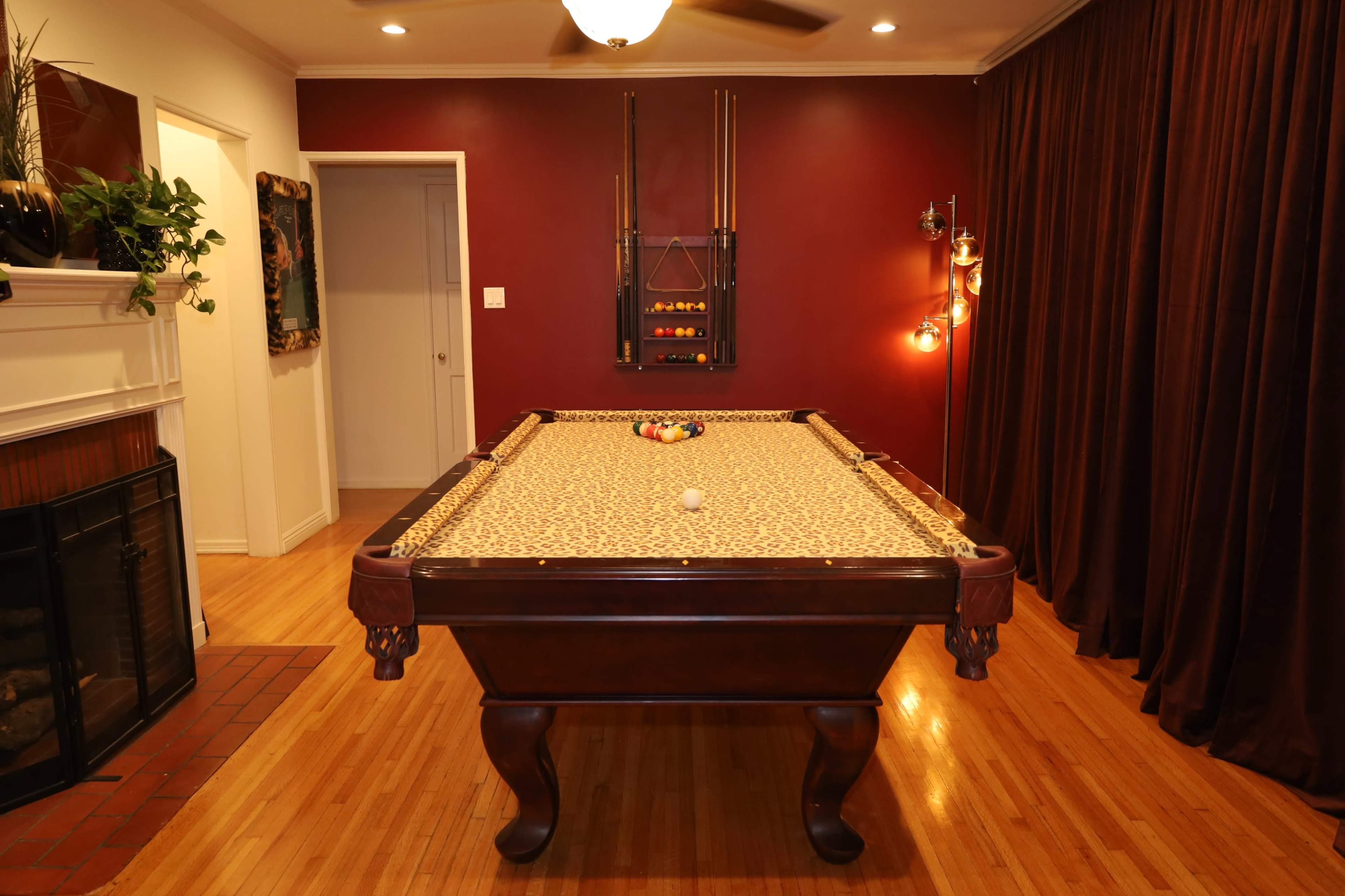 The image shows a billiards table in a room with dark red walls, a fireplace, and curtains.