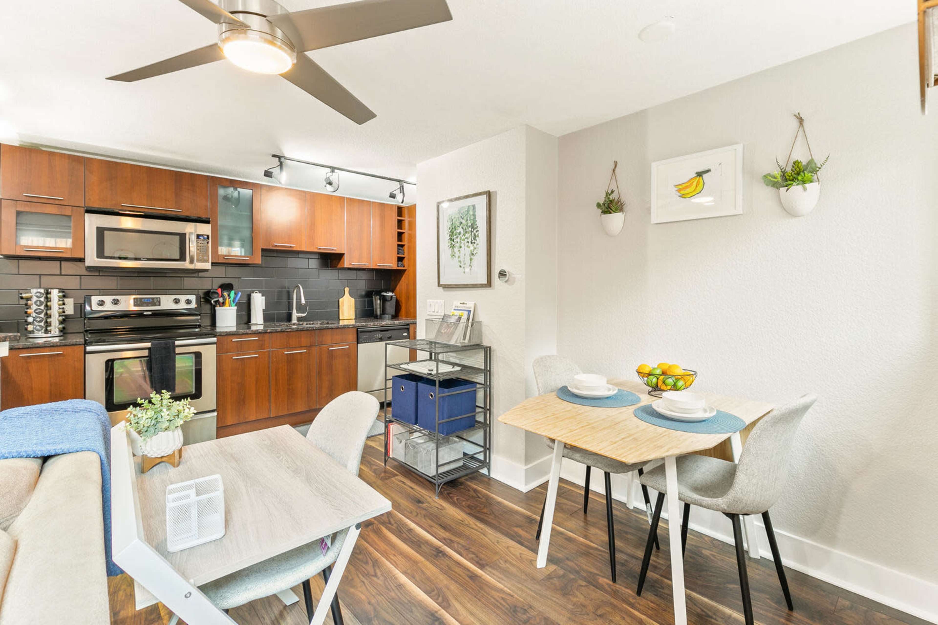 A modern kitchen and dining area feature wooden cabinetry, stainless steel appliances, and a small table set for two.