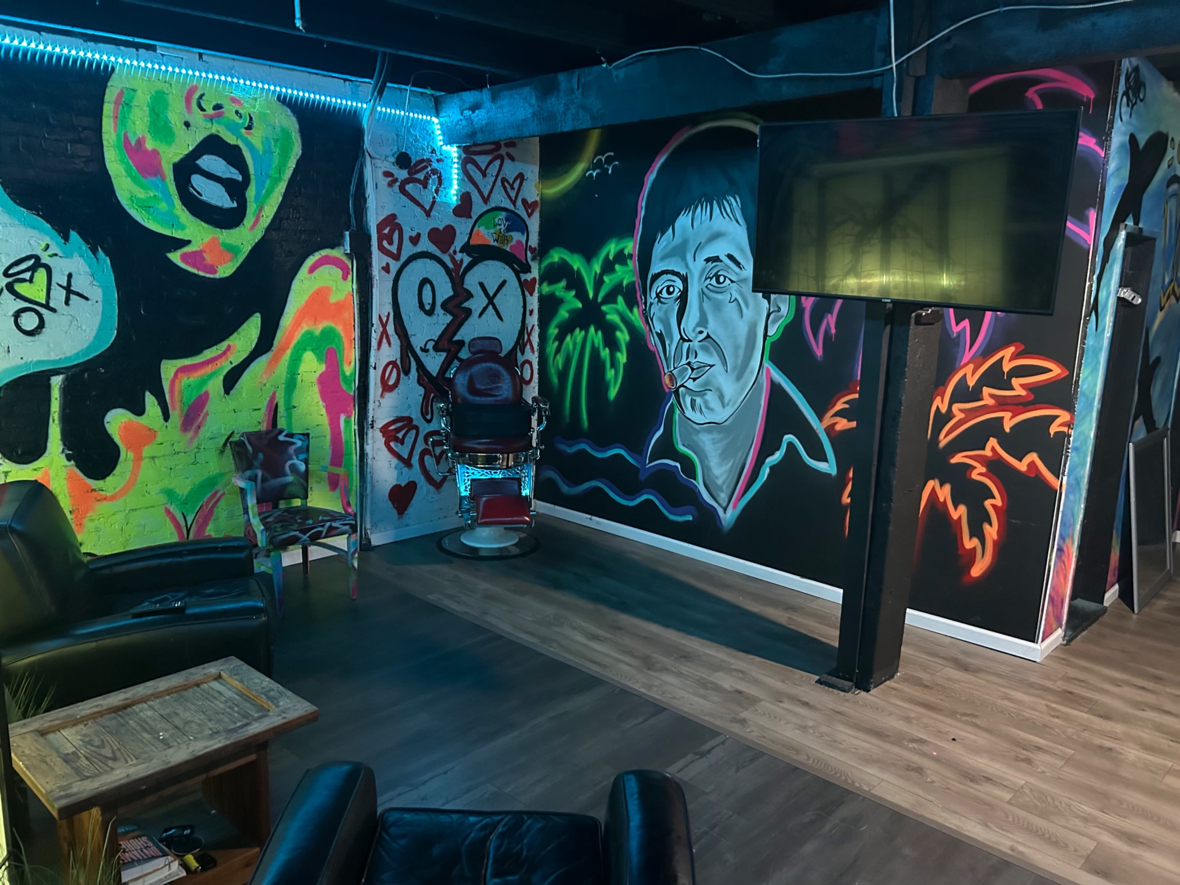 The image shows a dimly lit room with vibrant graffiti-style murals on the walls, including a portrait of a person and various colorful designs.