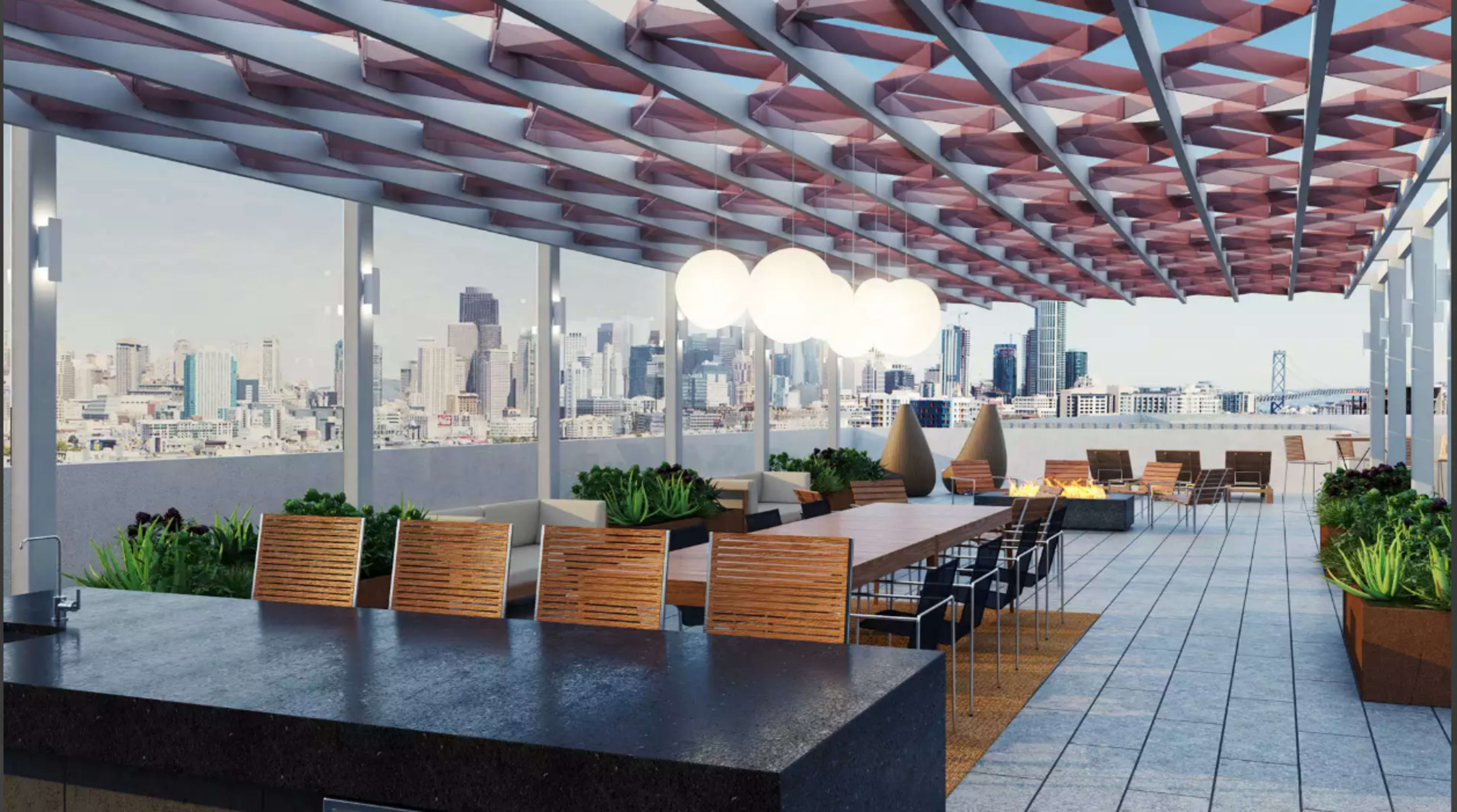A modern rooftop terrace featuring a long dining table, seating areas, and a fire pit, with a city skyline visible in the background.