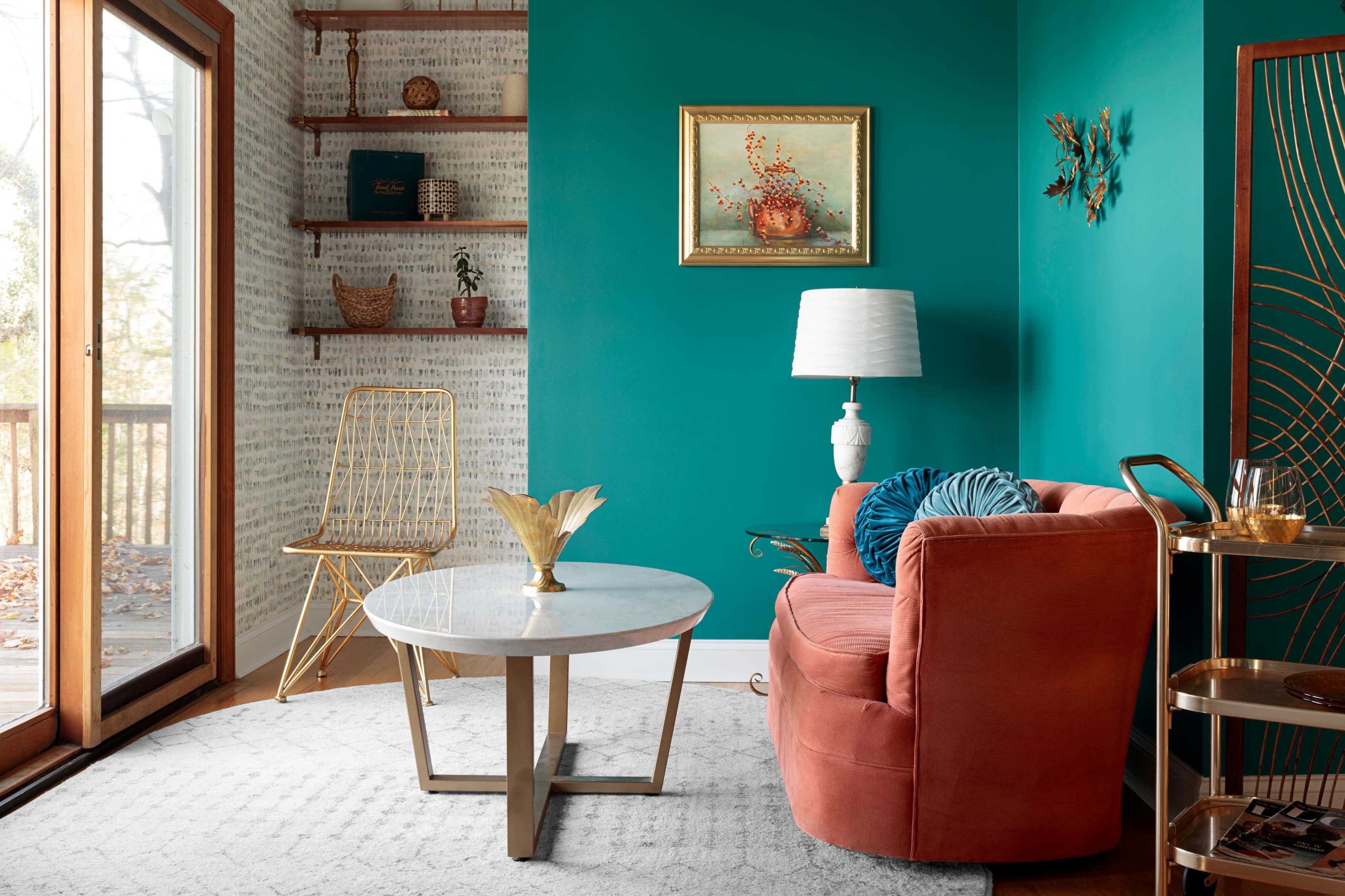 A cozy living room features a coral velvet sofa, a marble coffee table, and a turquoise wall with a potted plant on a shelf.