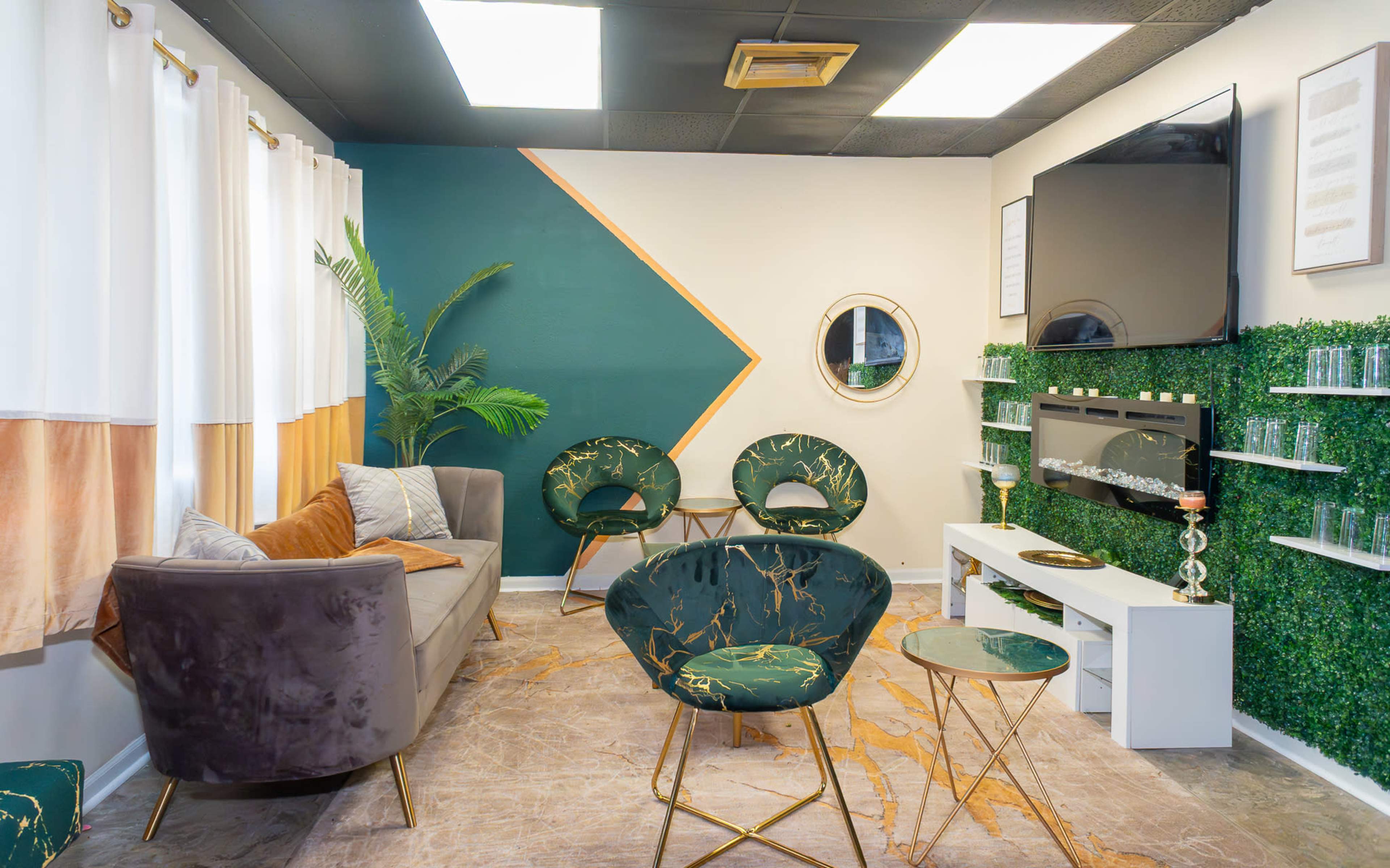 The image shows a modern lounge area with green accent walls, comfortable seating, and a wall-mounted television.