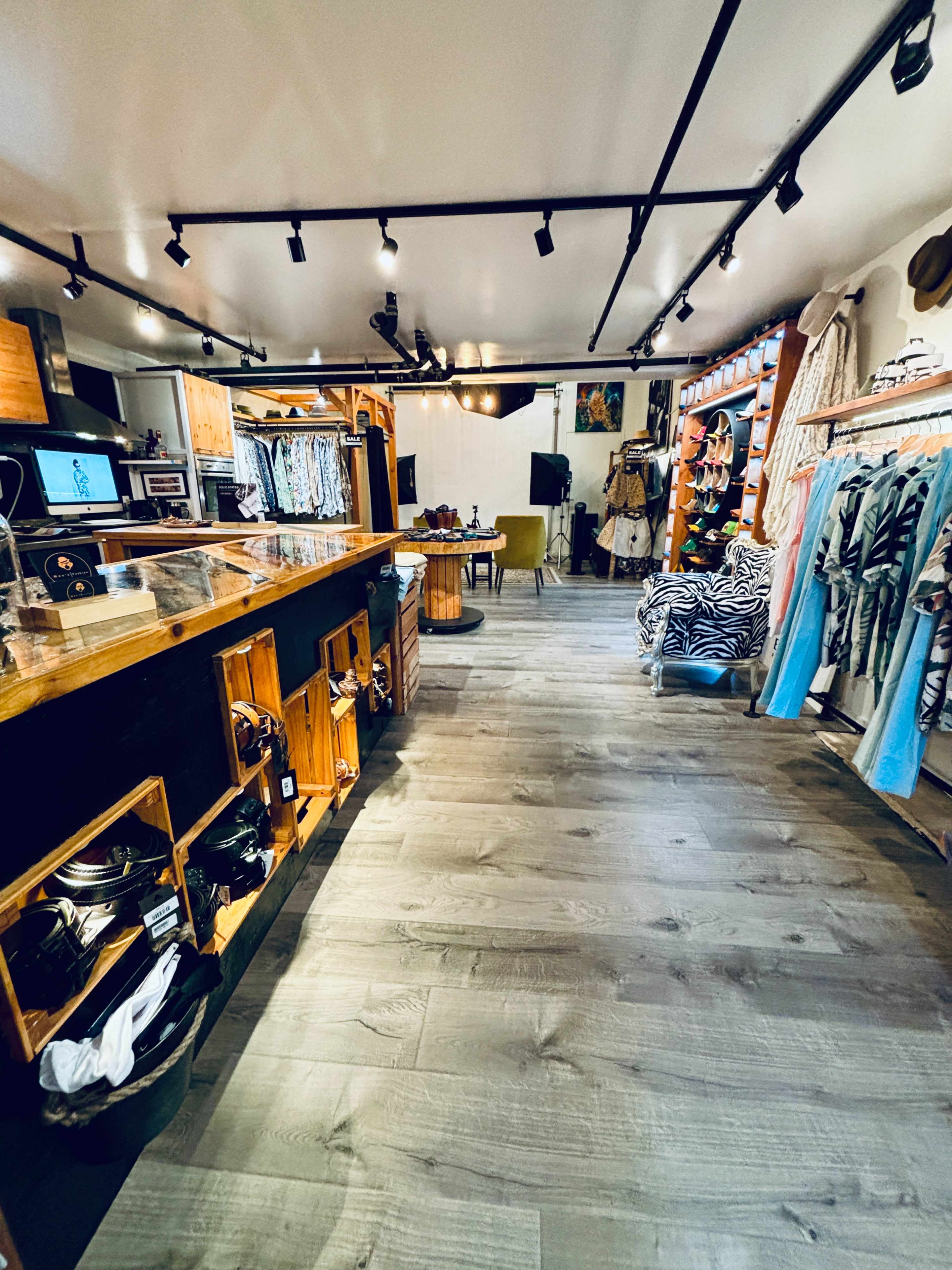 The interior of a retail store featuring wooden displays, clothing racks, and a spacious layout with natural lighting.