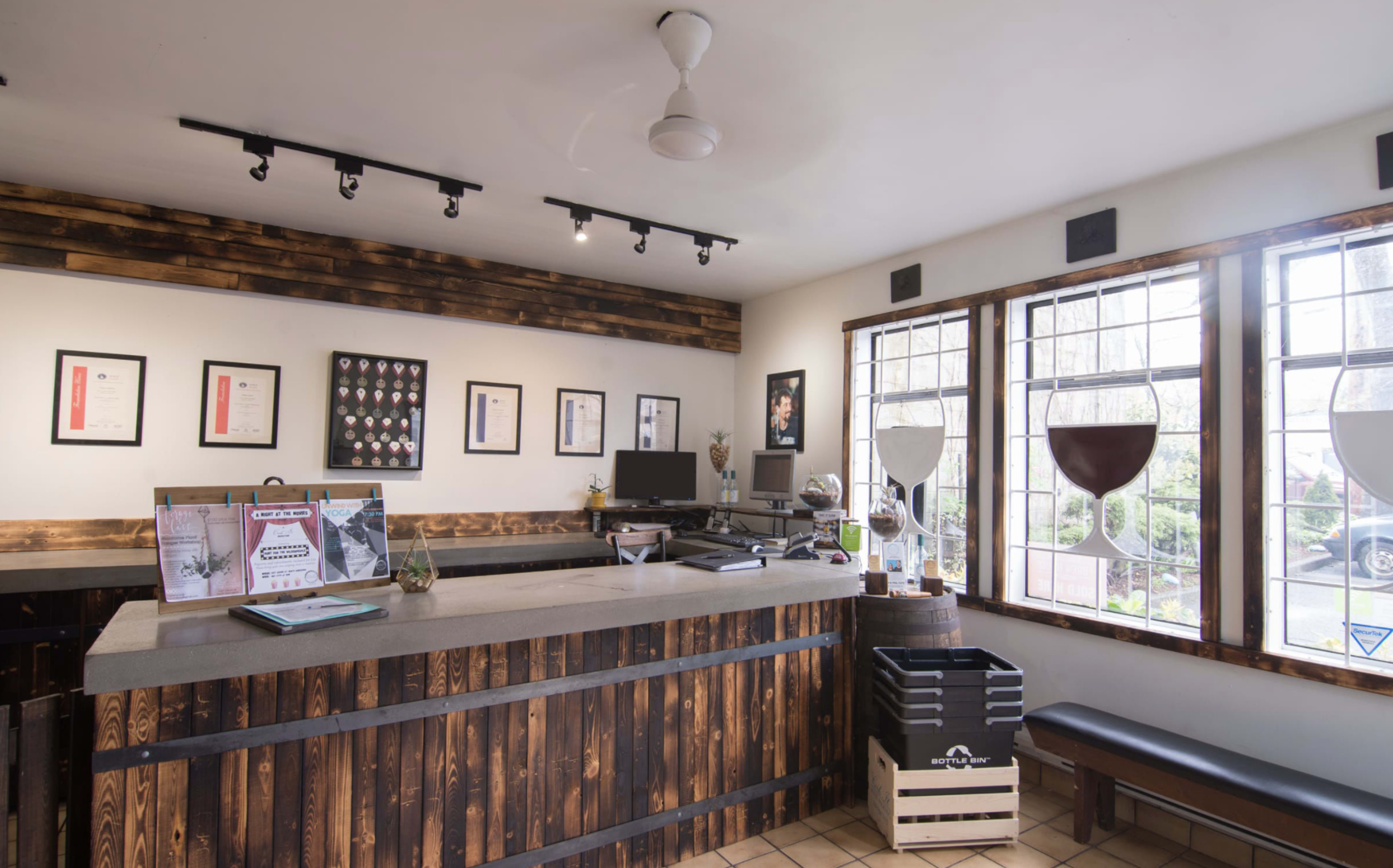 The scene shows a reception area with a wooden counter, framed certificates on the walls, and large windows allowing natural light to enter.