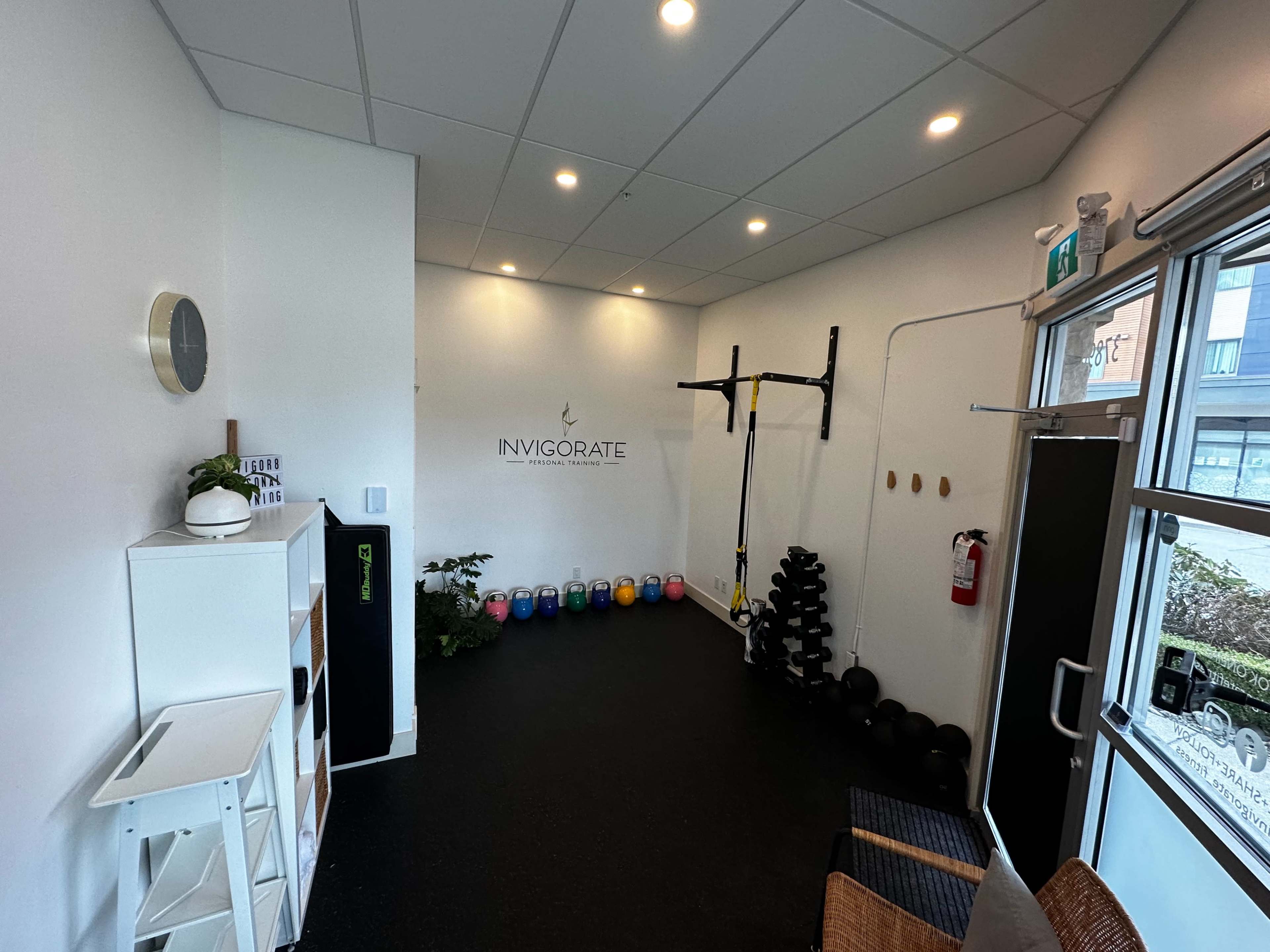 A fitness studio with wall-mounted exercise equipment, colorful weights lined up on the floor, and a minimalist design.