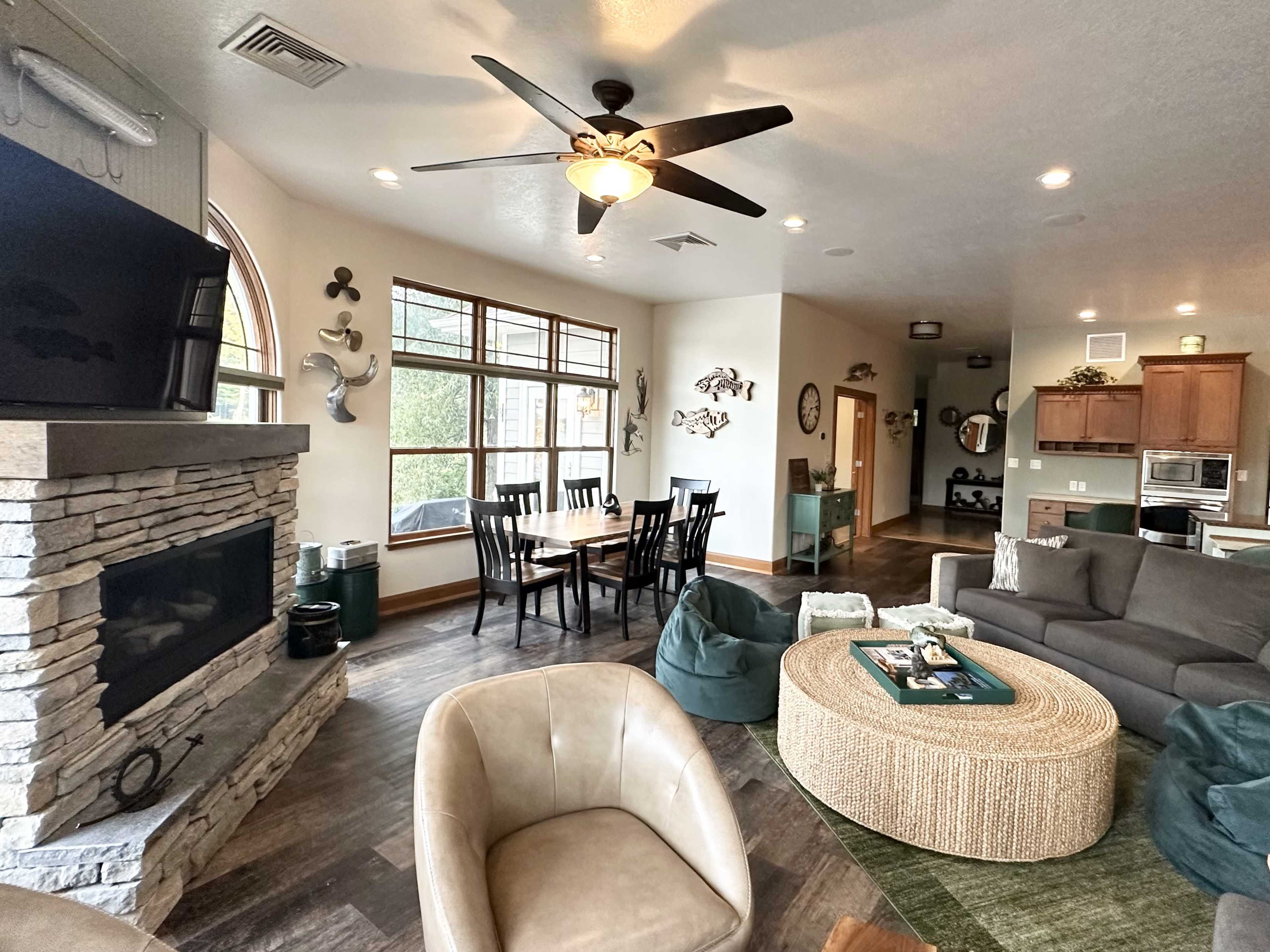 A cozy living area with a stone fireplace, a dining table, and comfortable seating arranged around a round coffee table.