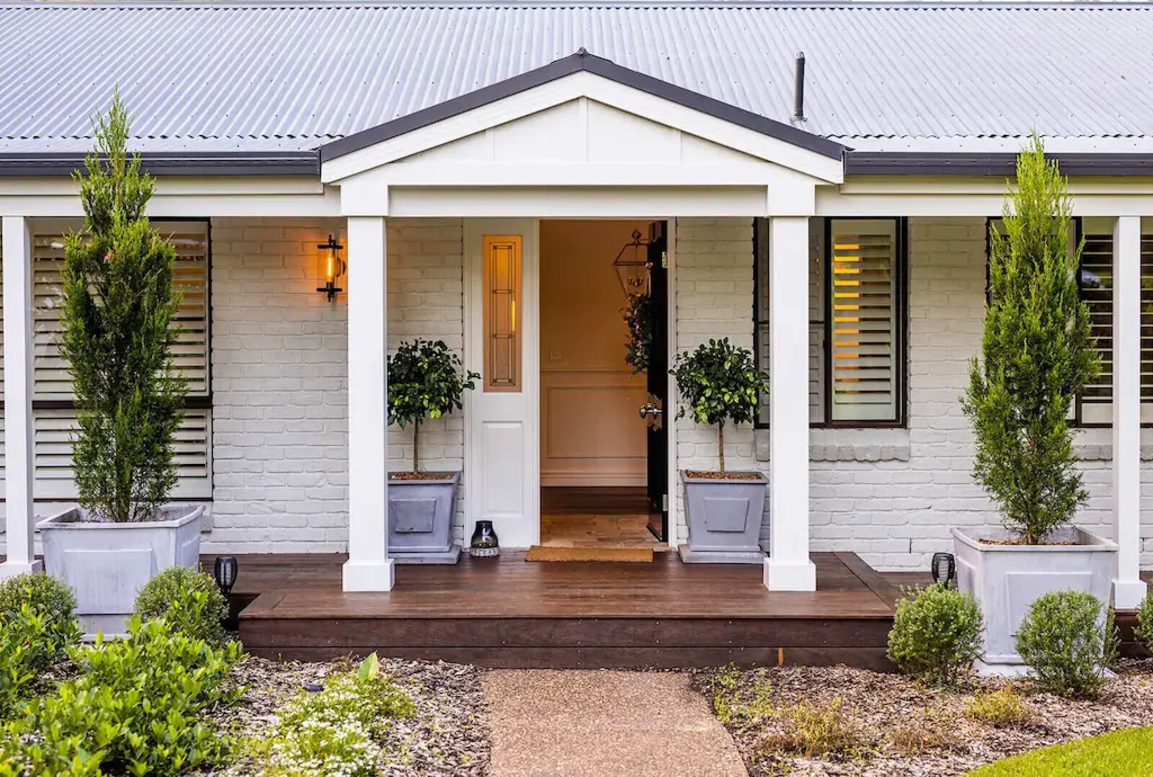 The entrance of a house featuring a covered porch with two planters and a welcoming front door.