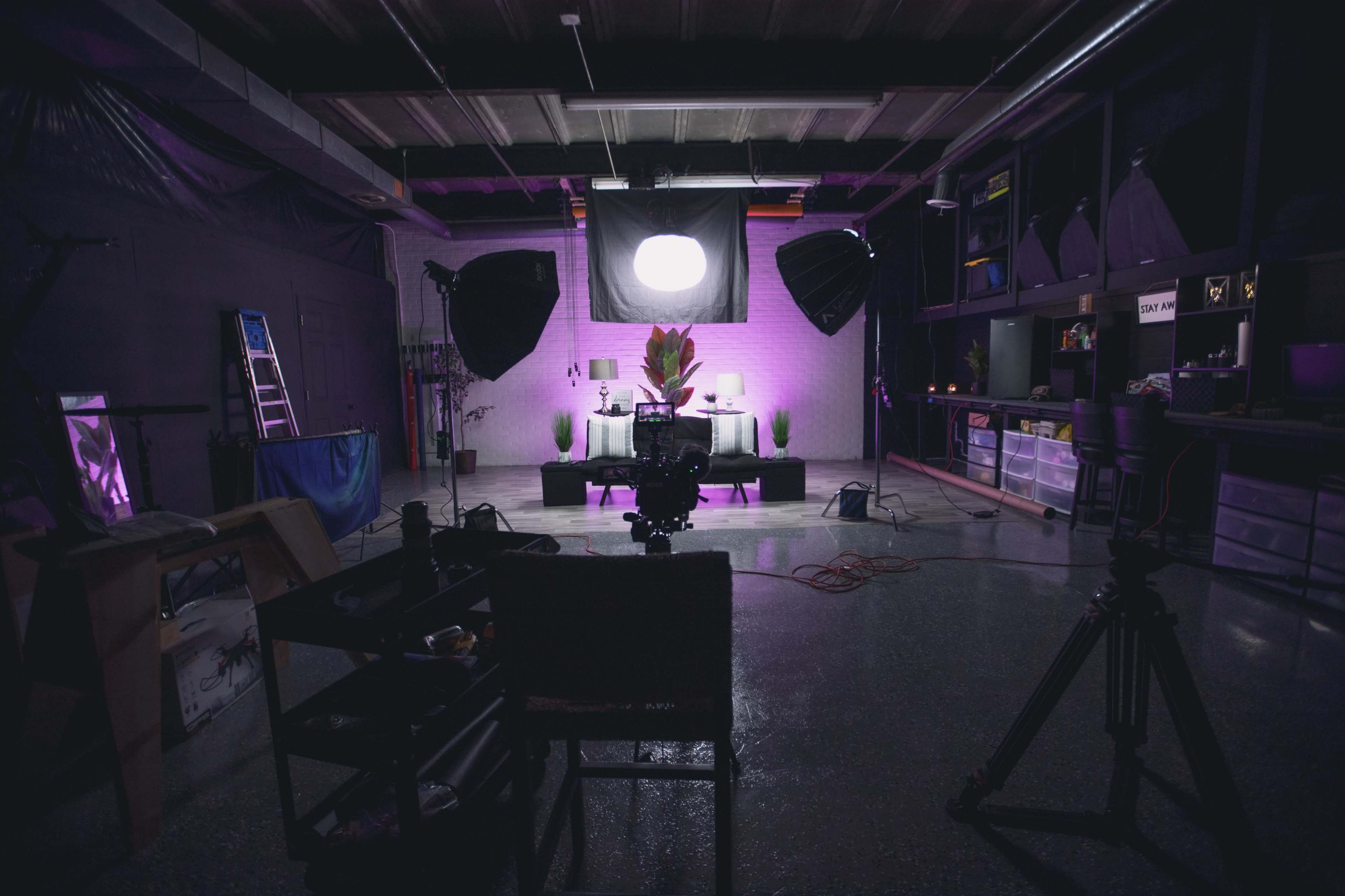 A photography studio is set up with lighting equipment, a backdrop, and various props arranged in a dimly lit space.